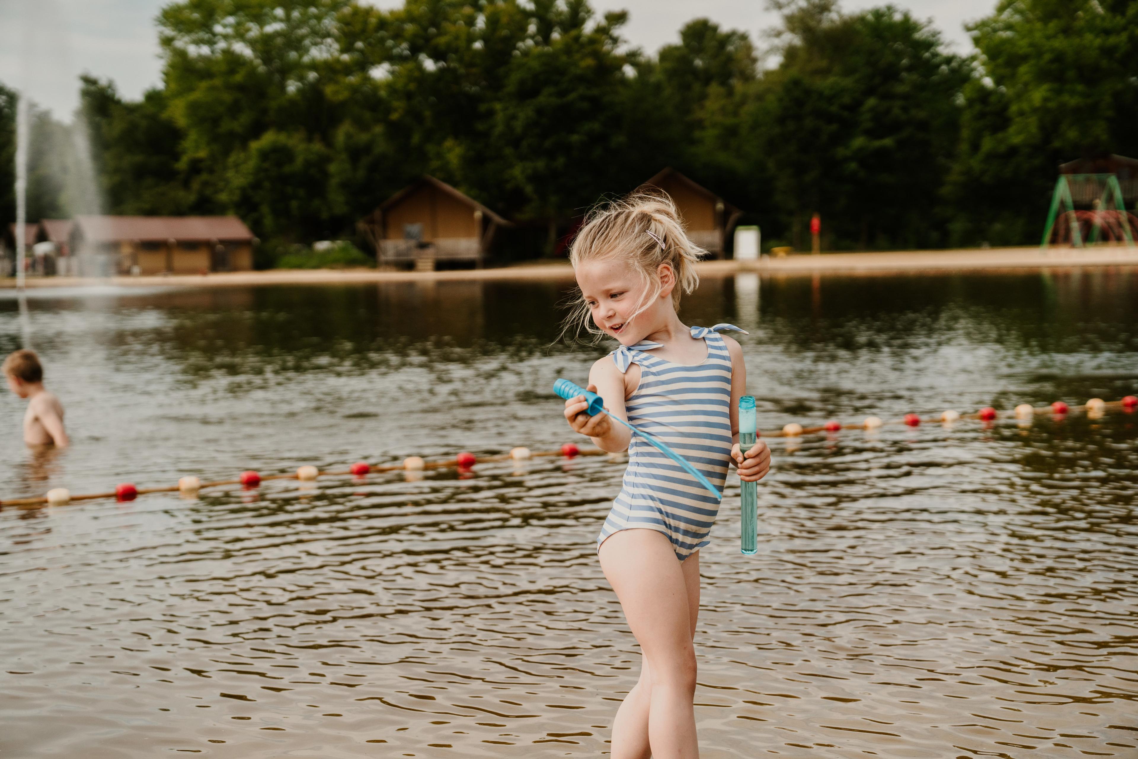 Meisje aan het spelen met bellenblaas bij de zwemvijver van Vakantiepark Dierenbos