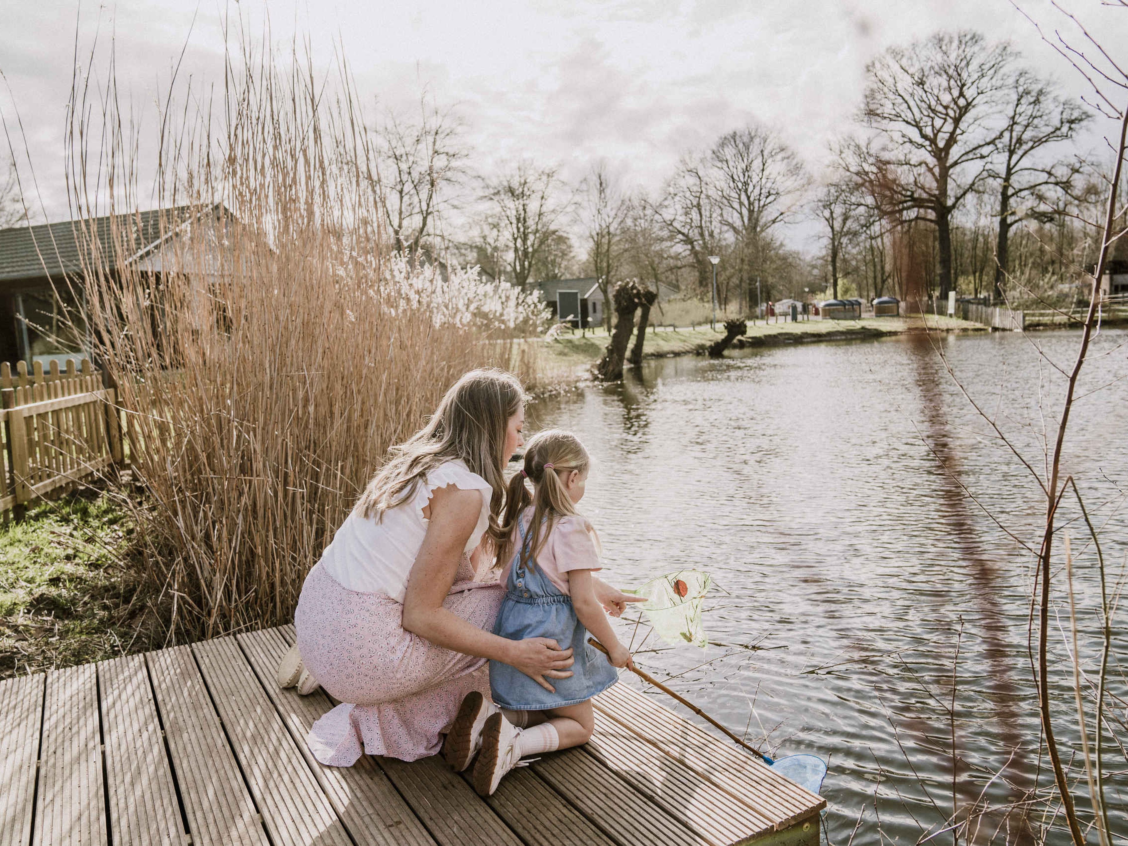 Moeder en kind met visnet op de steiger van de visvijver van Vakantiepark Dierenbos