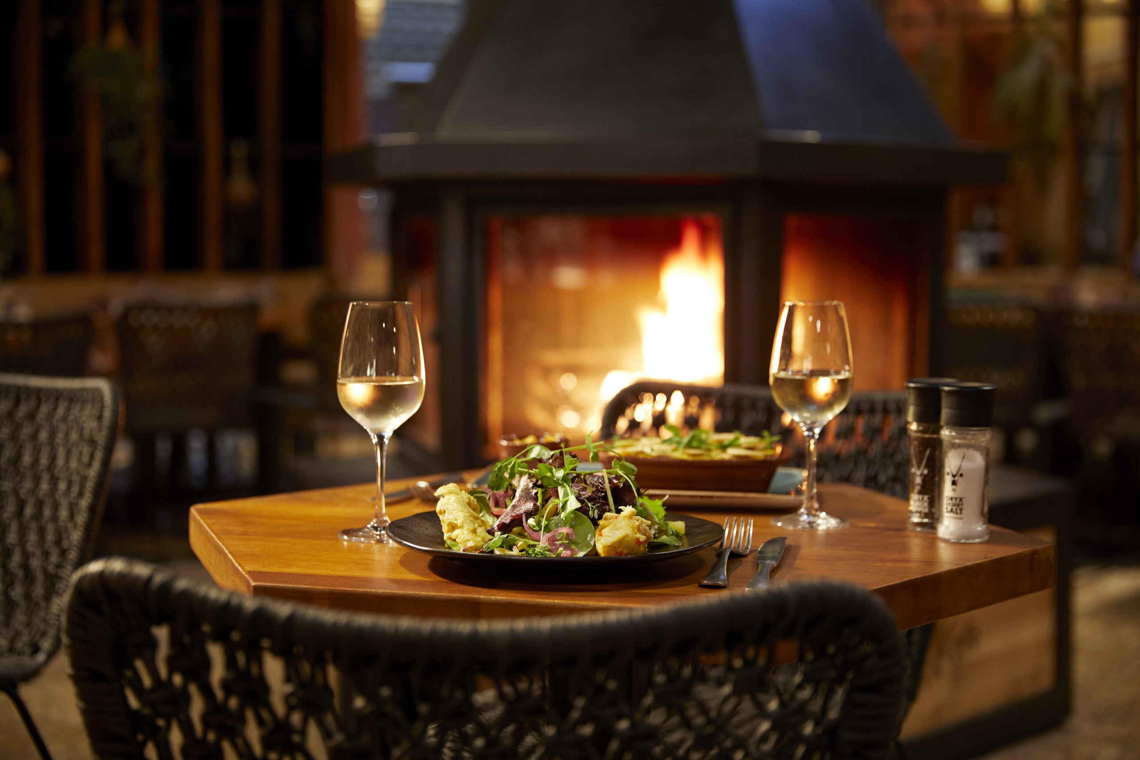 Een tafel met hoofdgerechten en twee glaze witte wijn bij restaurant Moto in Safari Resort Beekse Bergen.