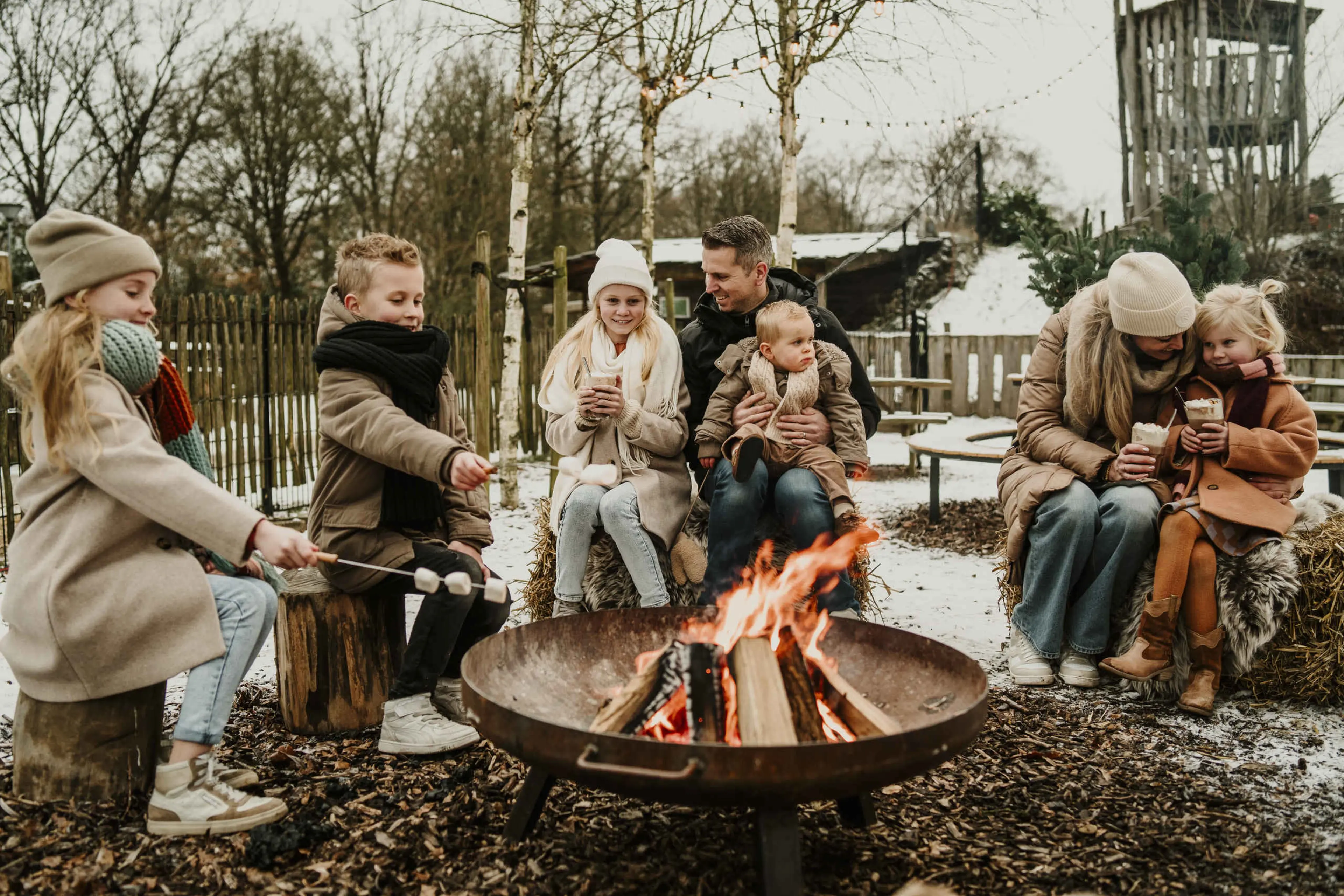 Een familie zit rond het kampvuur bij Vakantiepark Dierenbos.