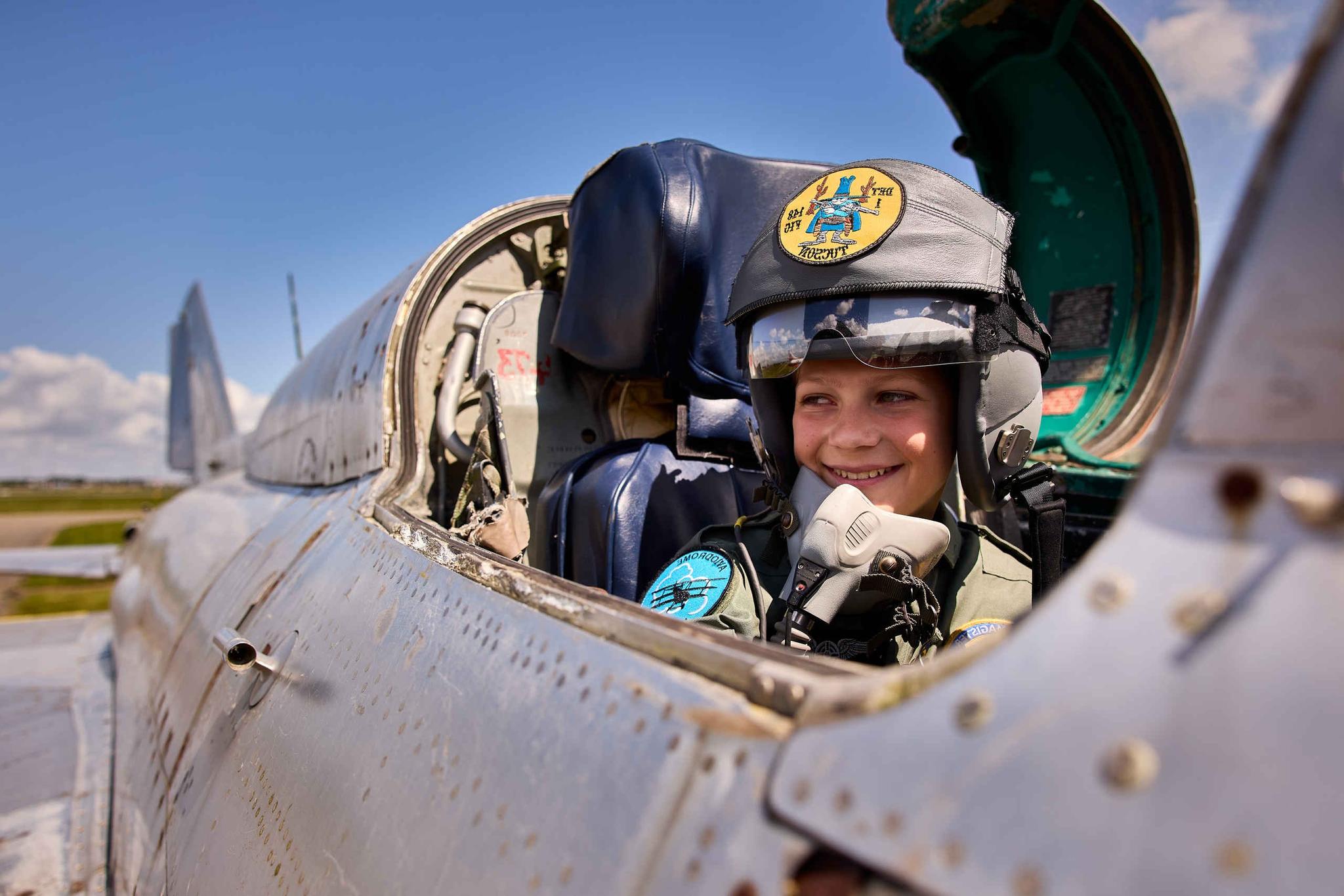 Jongen in de cockpit van een straaljager tijdens de straaljagerweken expositie bij Luchtvaartmuseum Aviodrome