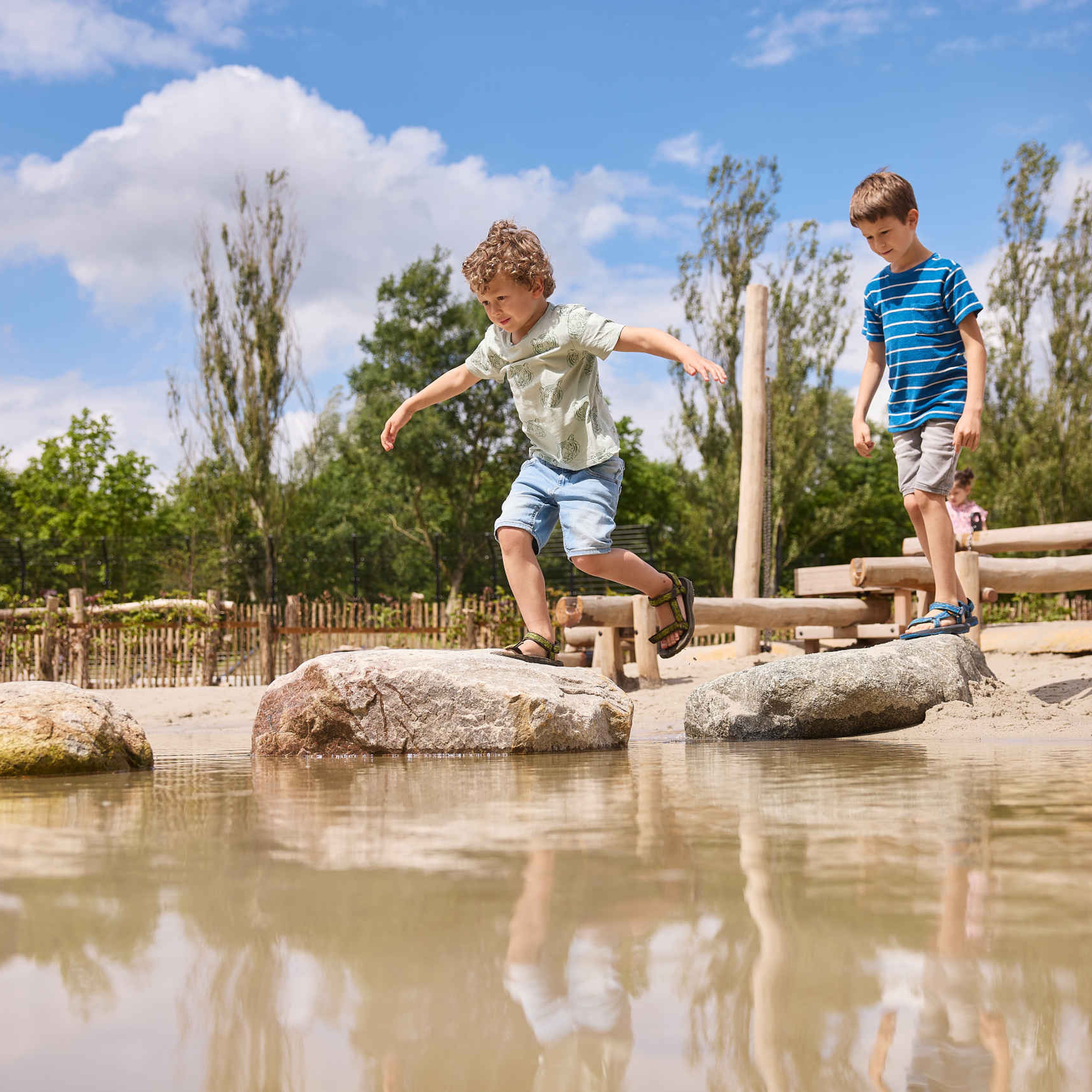 Twee jongens lopen over de stenen in het water bij de waterspeeltuin in Eindhoven Zoo.