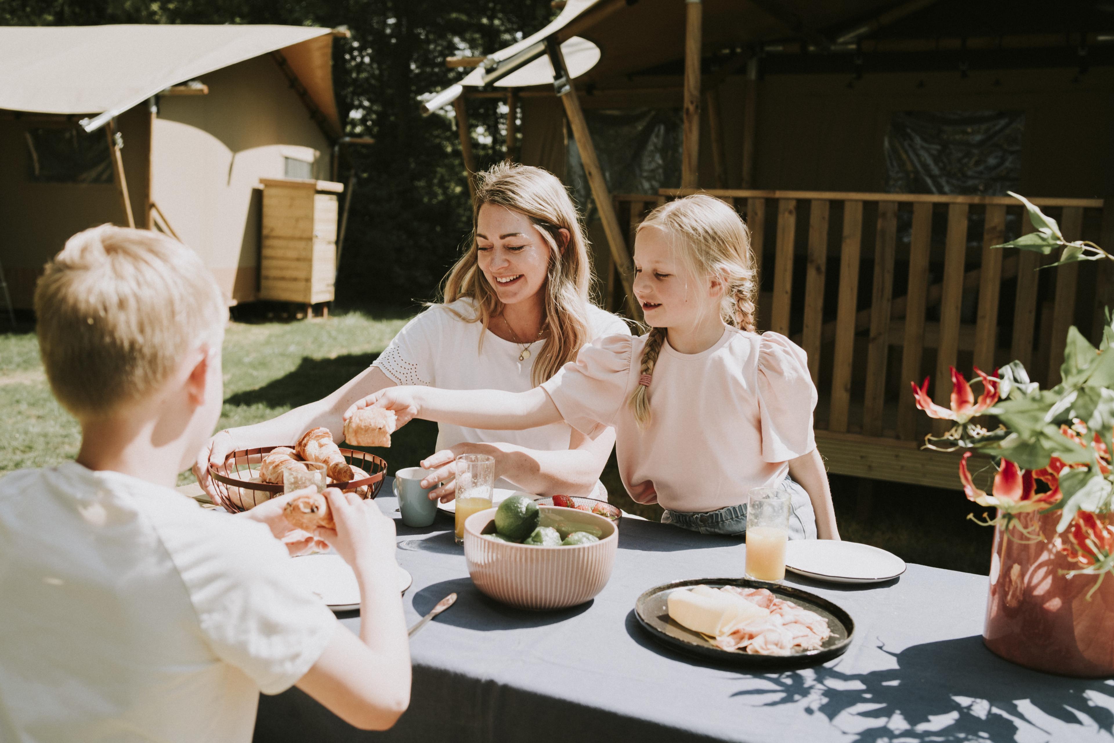 Gezin aan het ontbijten aan een picknicktafel bij Vakantiepark Dierenbos