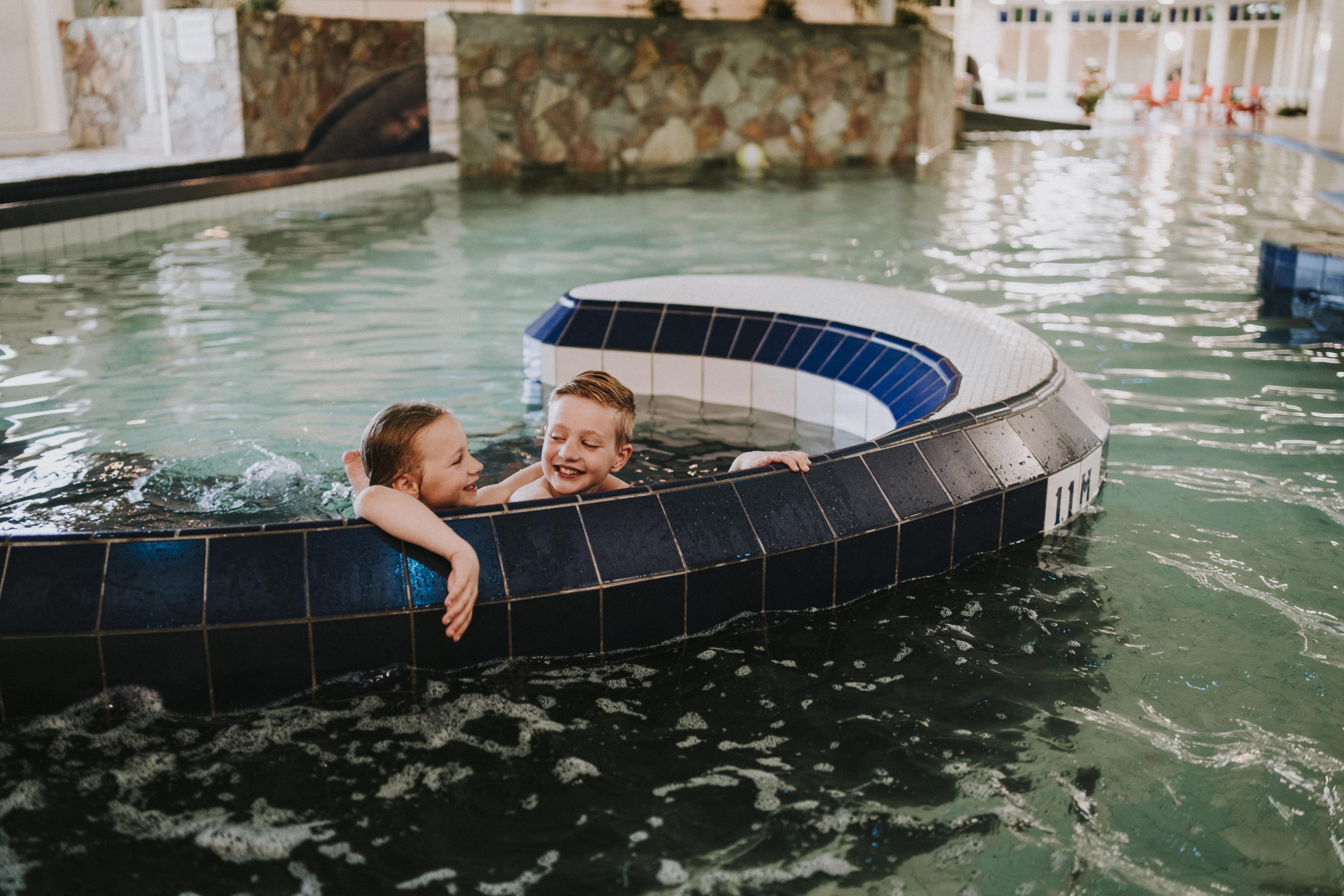 Kinderen hangen aan de rand van het zwembad bij Vakantiepark Dierenbos