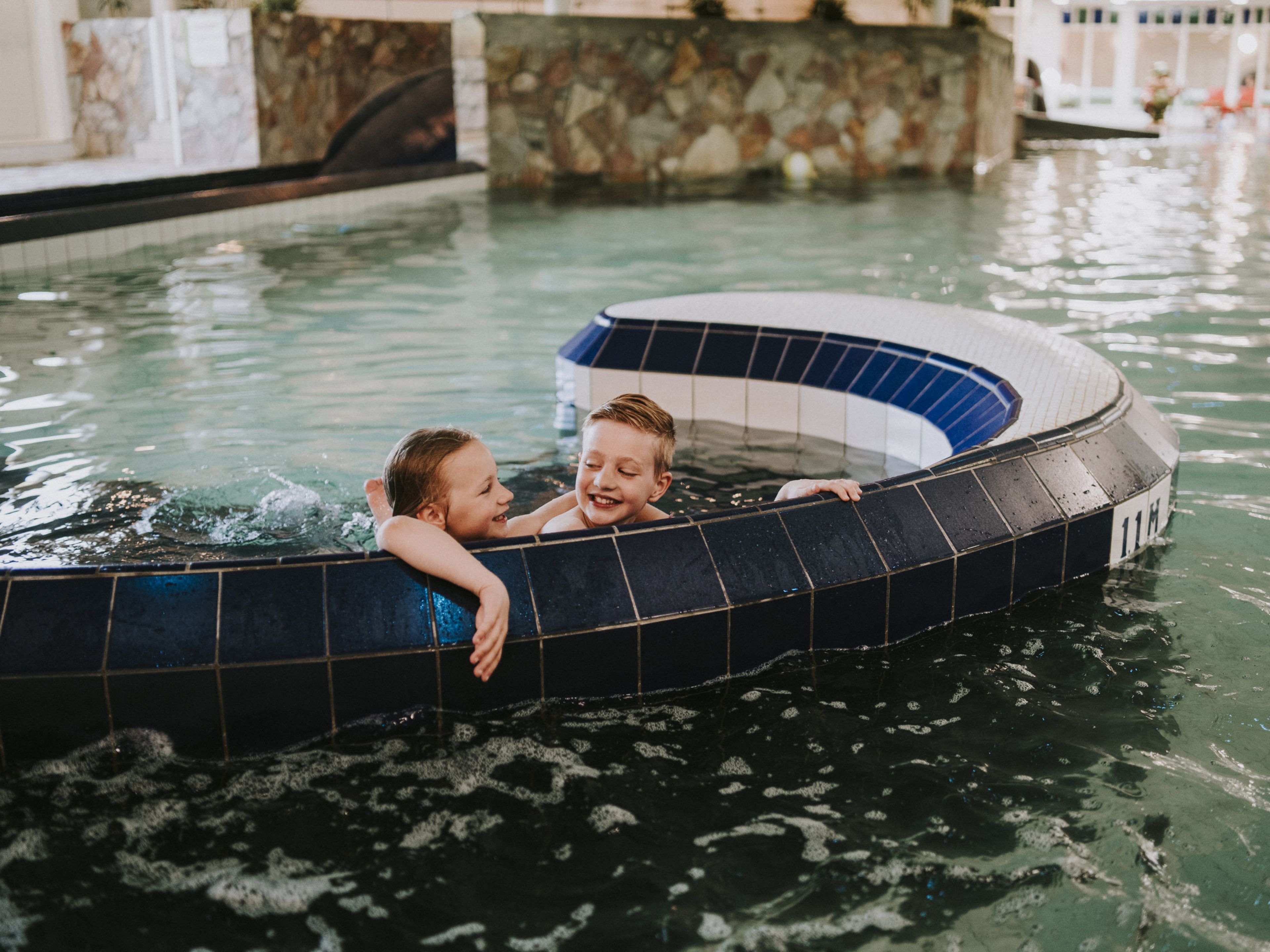 Kinderen hangen aan de rand van het zwembad bij Vakantiepark Dierenbos