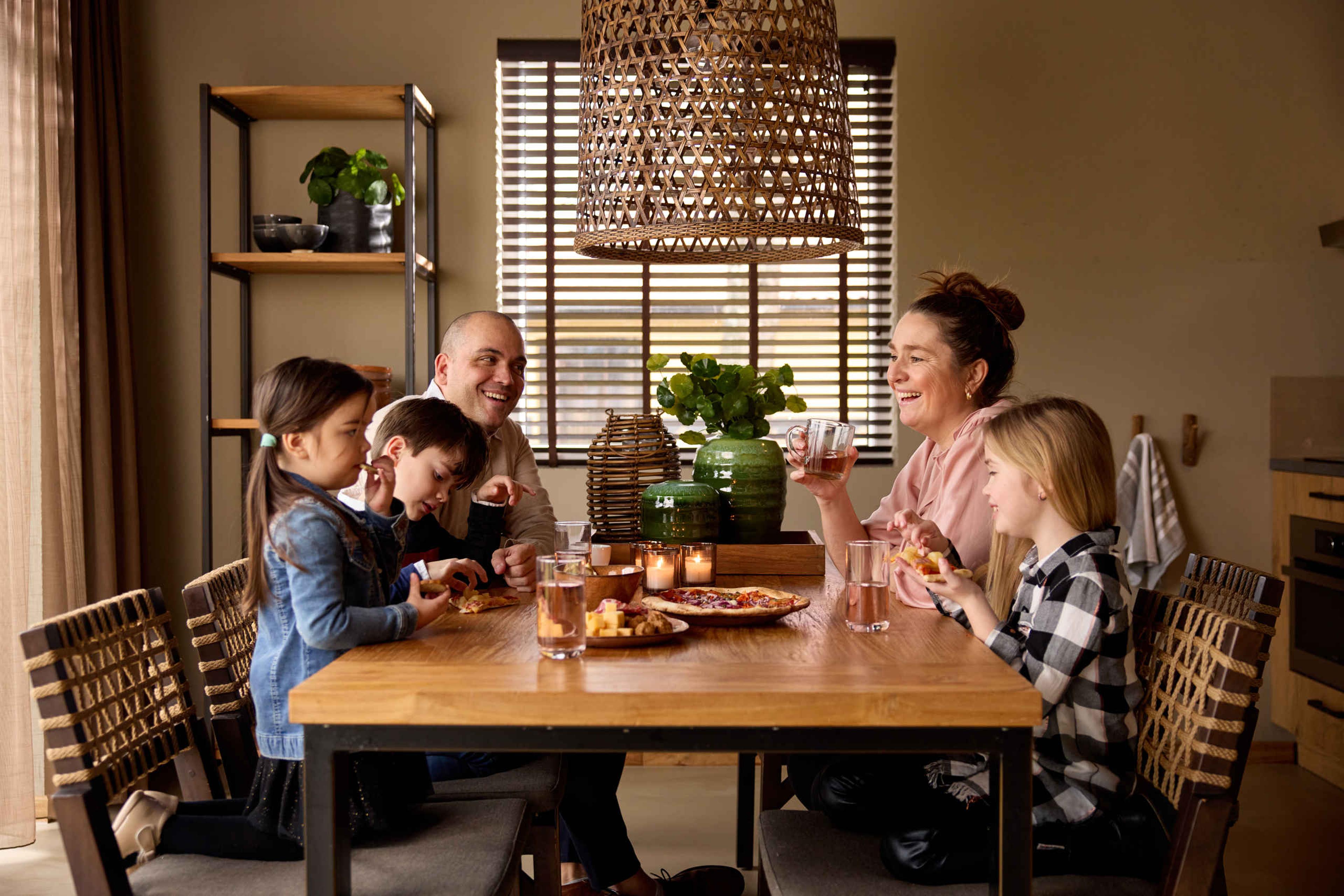 Gezin met een hapje en drankje aan tafel in de Savanne Lodge op Safari Resort Beekse Bergen