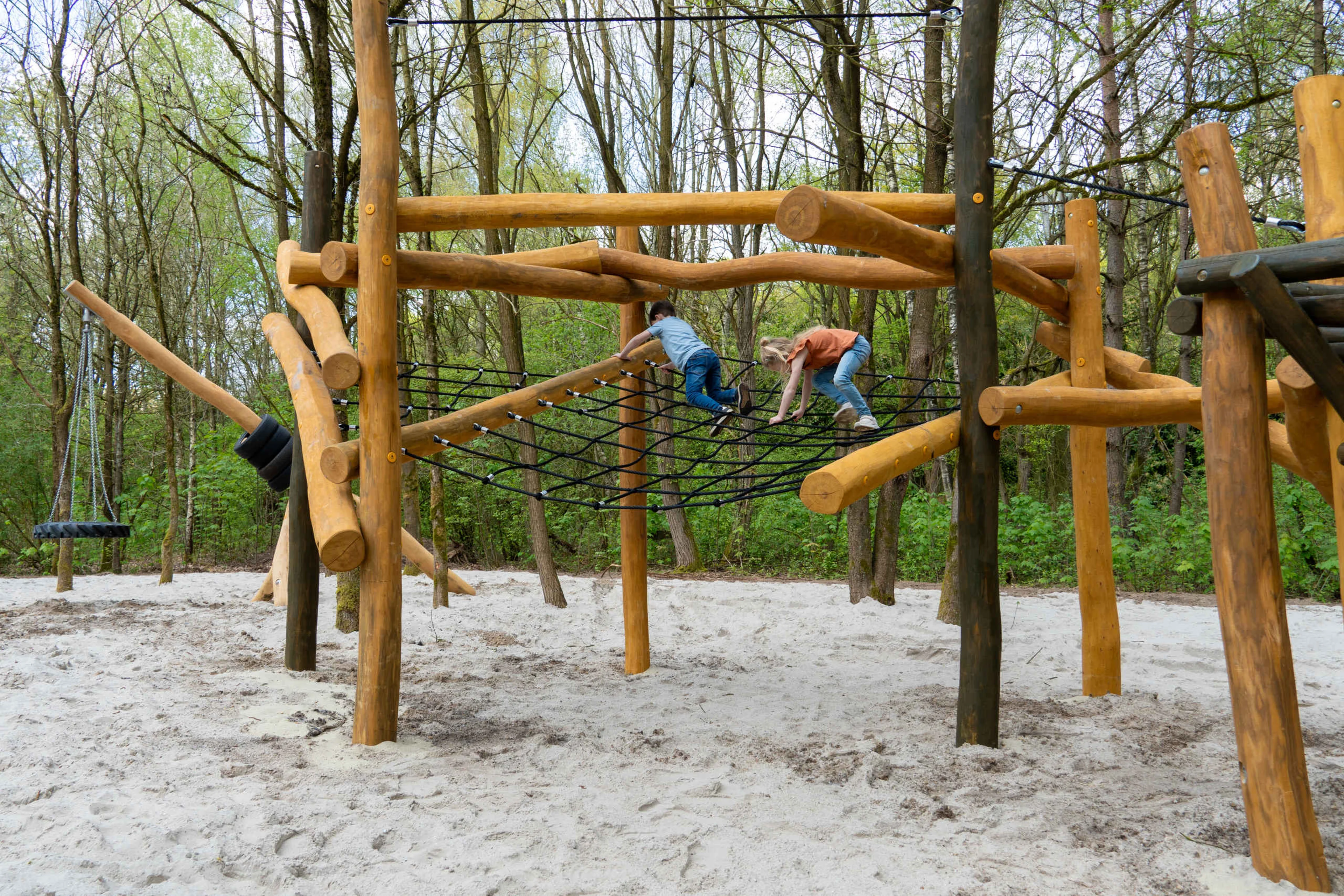Twee kinderen klimmen op het klimrek bij de speeltoren in het Speelbos van Klimrijk Brabant