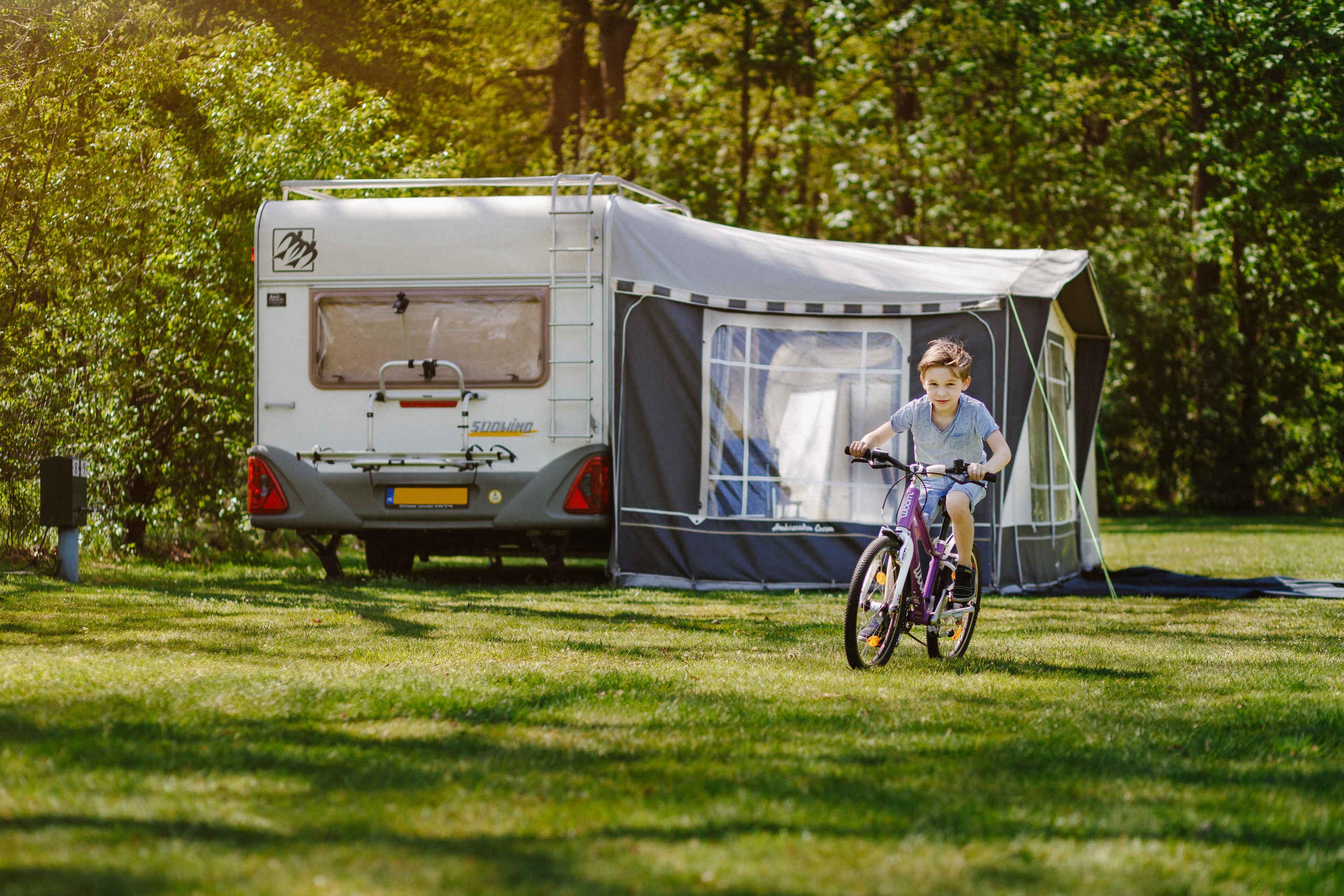 Een jongen fietst over het kampeerveld bij de comfort kampeerplaats op Lake Resort Beekse Bergen.