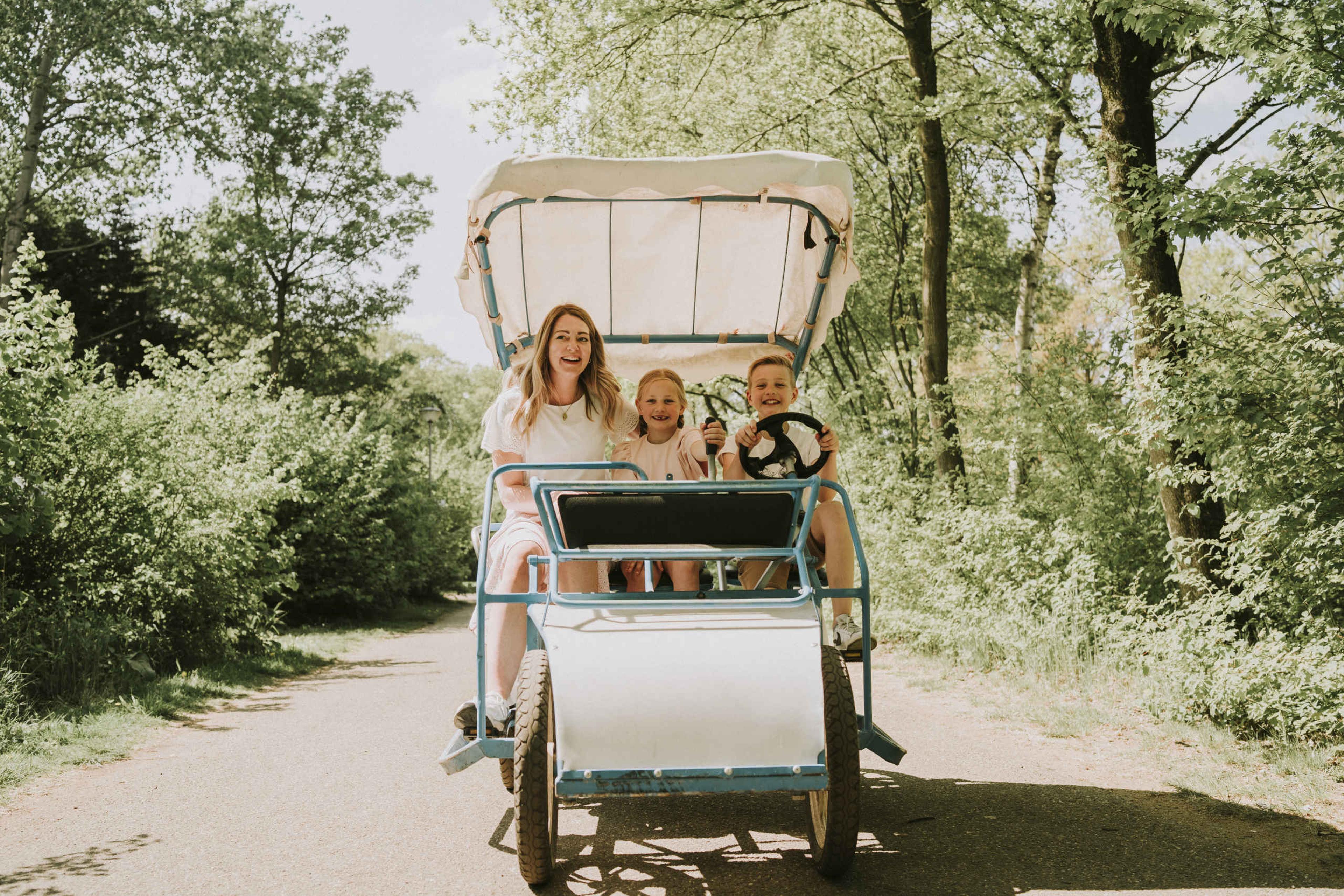 Een vrouw en haar kinderen fietsen in een gehuurde fiets van Vakantiepark Dierenbos.