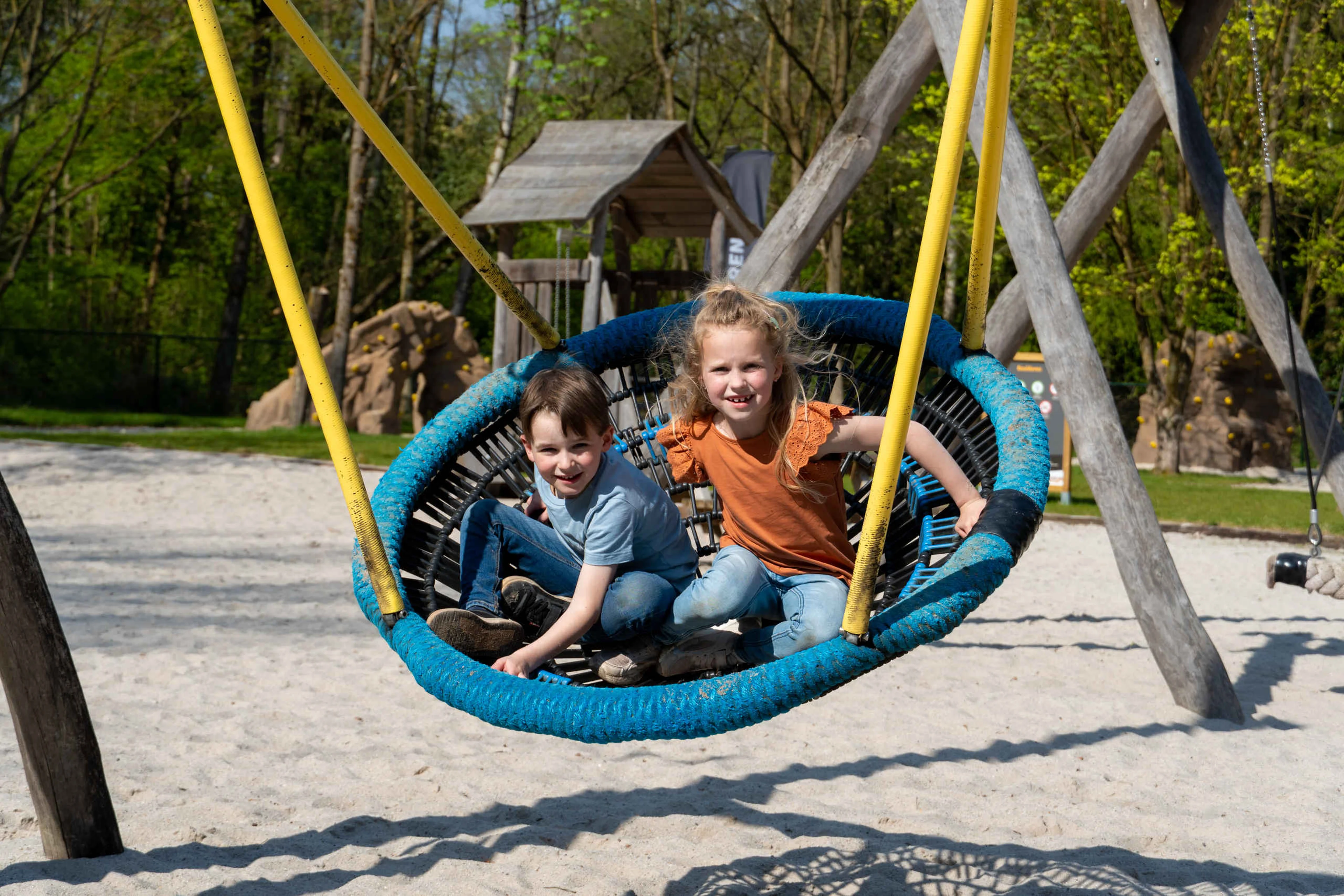 Twee kinderen in de schommel in de speeltuin bij Klimrijk Brabant