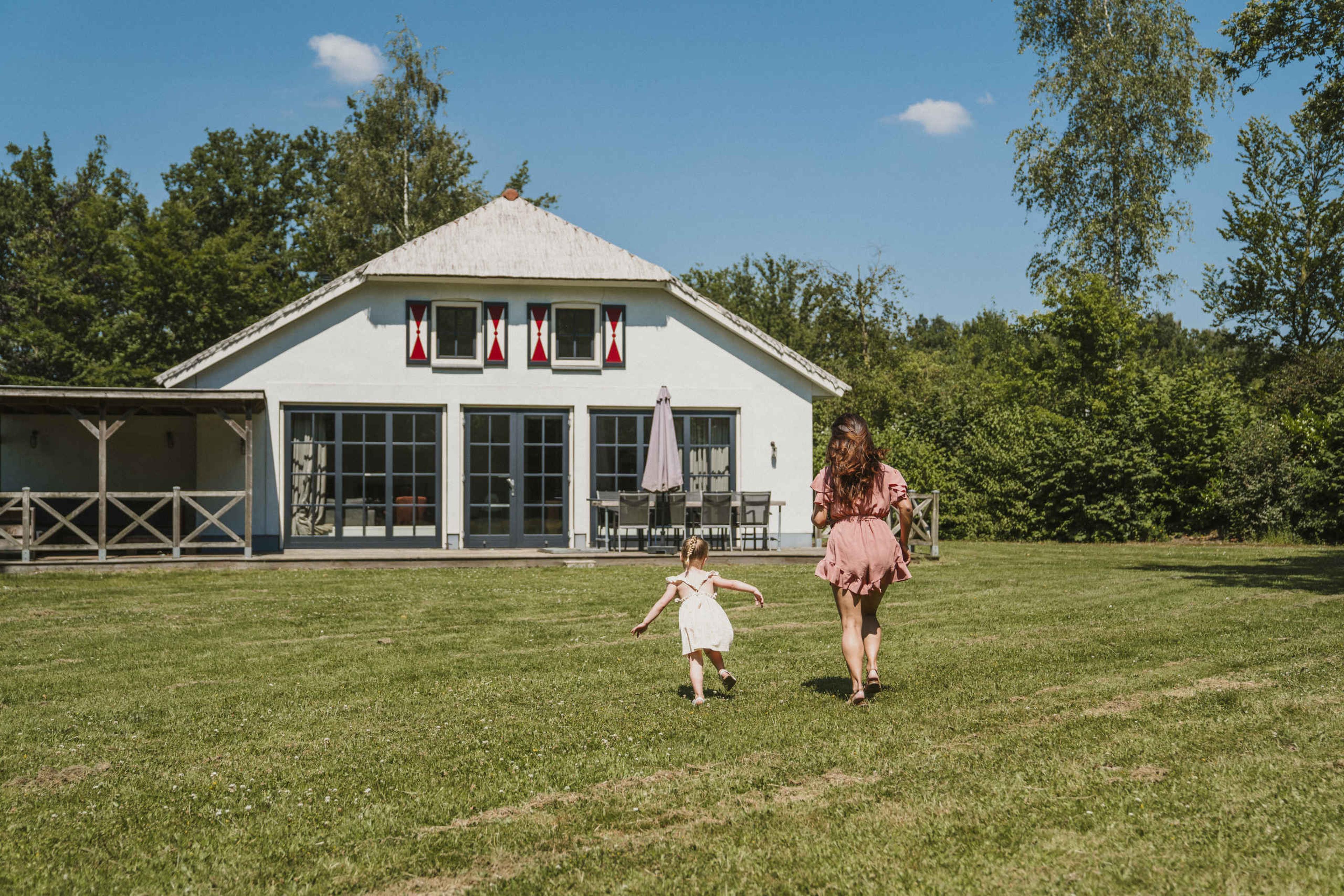 Een moeder en haar dochter rennen in het grasveld bij Villa Alpaca bij Vakantiepark Dierenbos
