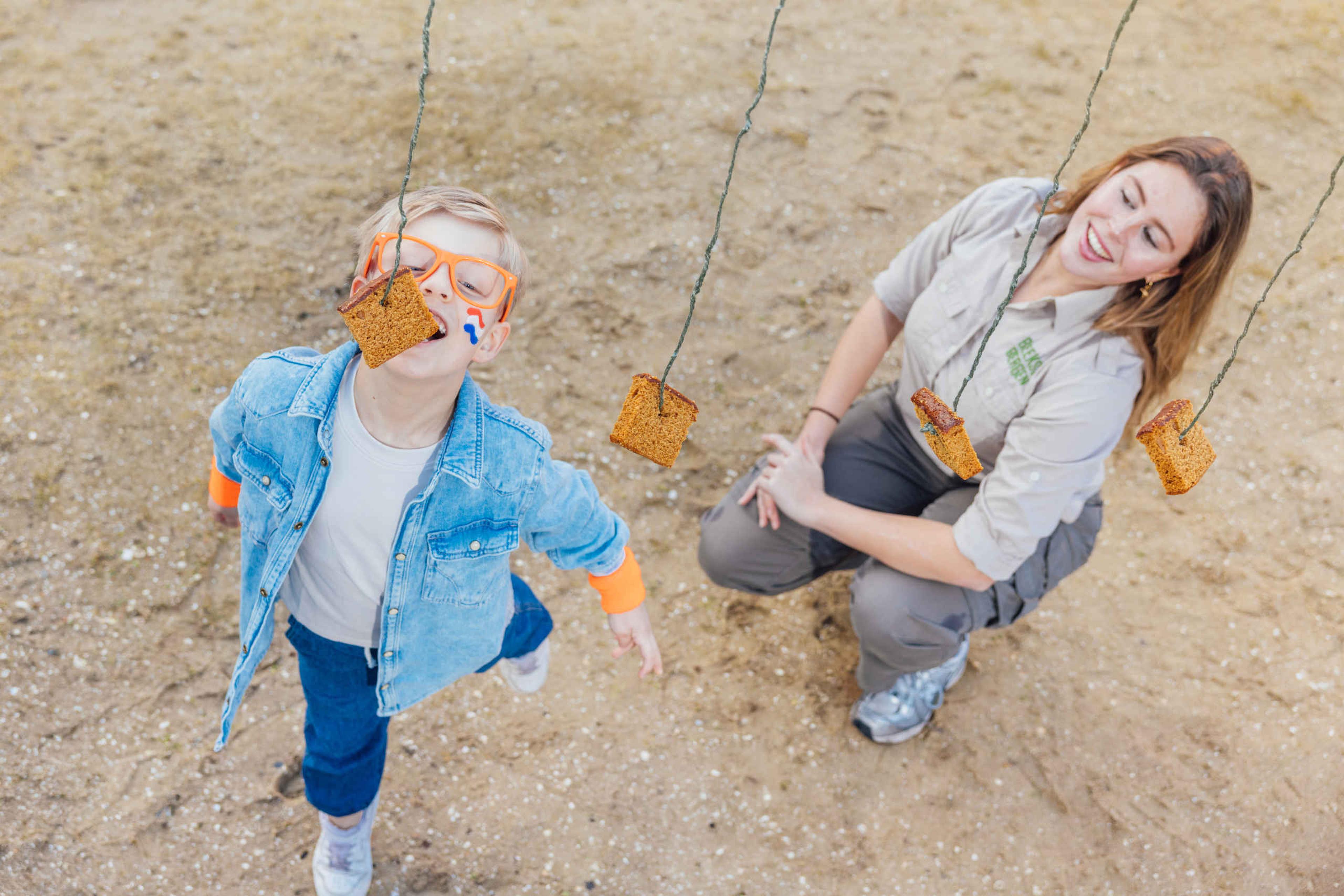 Een jongen is aan het koekhappen tijdens de koningsspelen bij Lake Resort Beekse Bergen.