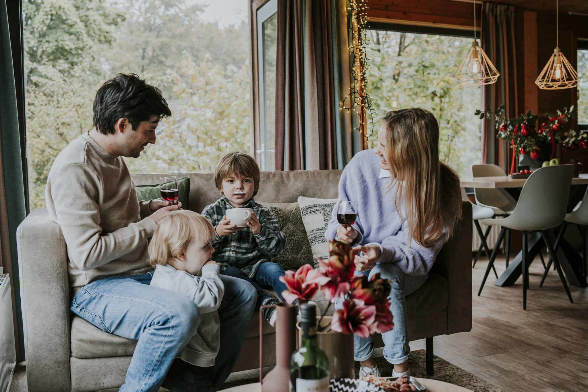 Gezin op de bank in de woonkamer met chocomel bij Vakantiepark Dierenbos