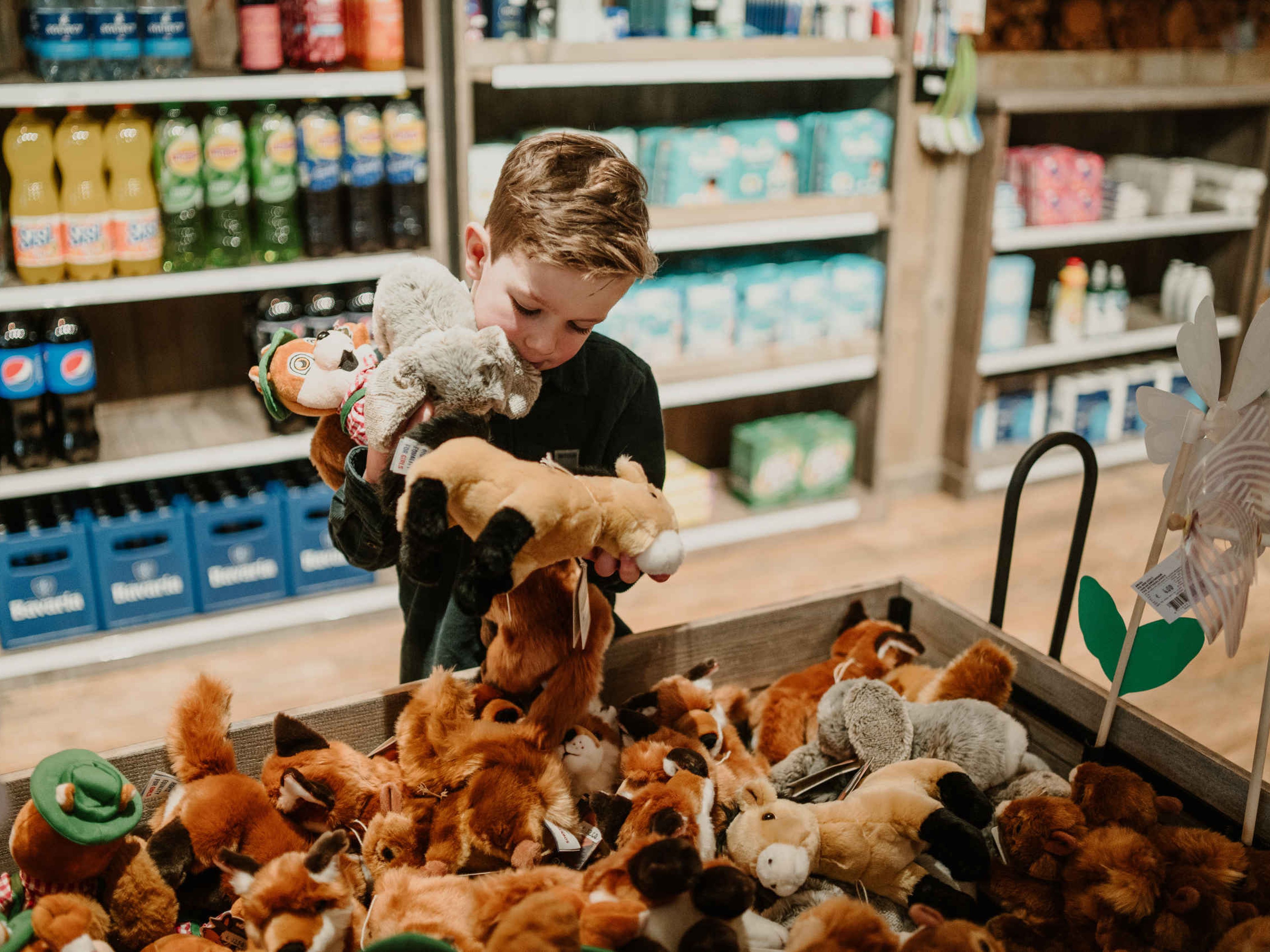 Een jongen kijkt bij de knuffels bij mini-market Broodnodig bij Vakantiepark Dierenbos.