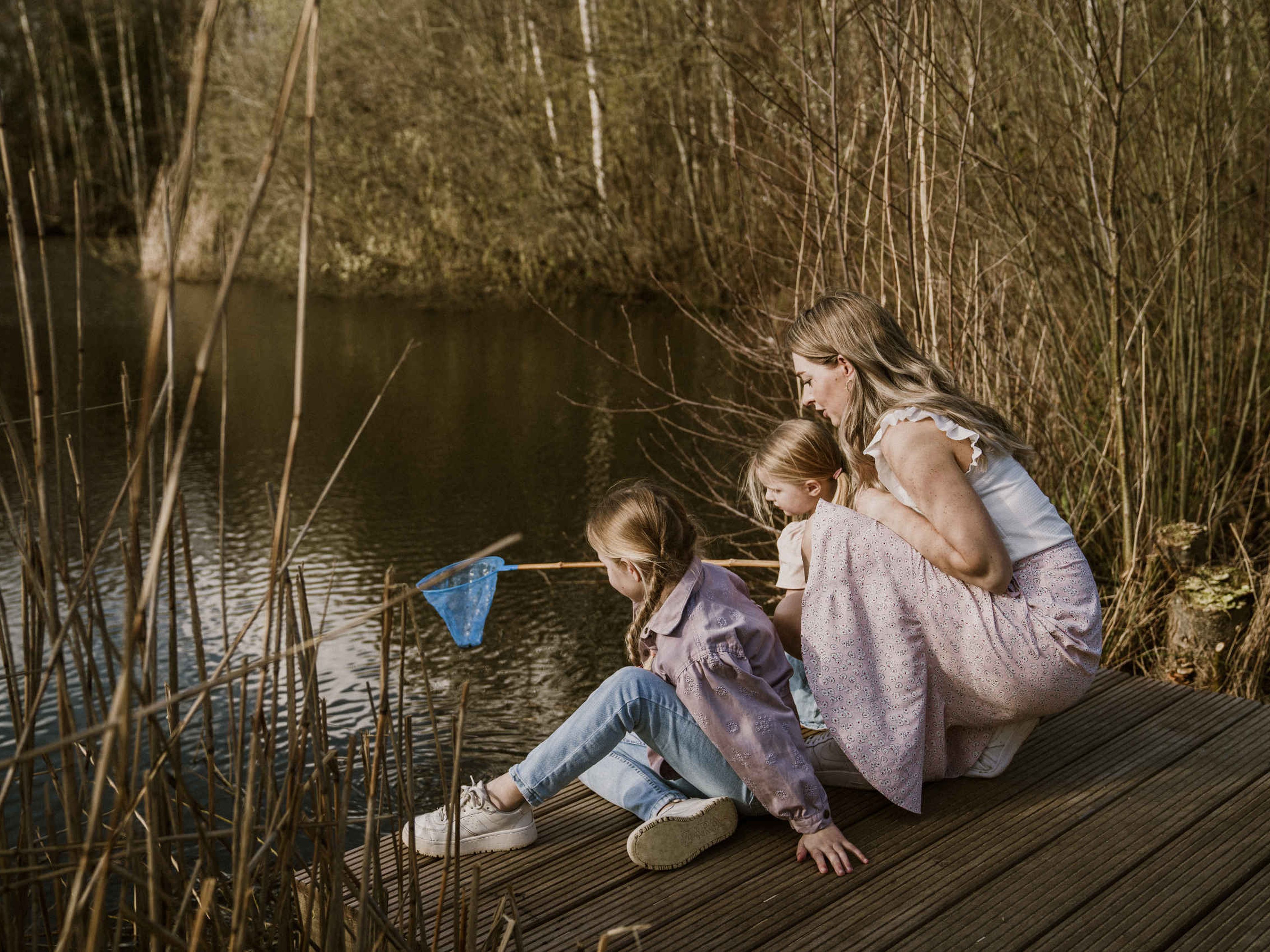 Moeder met kinderen met visnet op de steiger van de visvijver van Vakantiepark Dierenbos