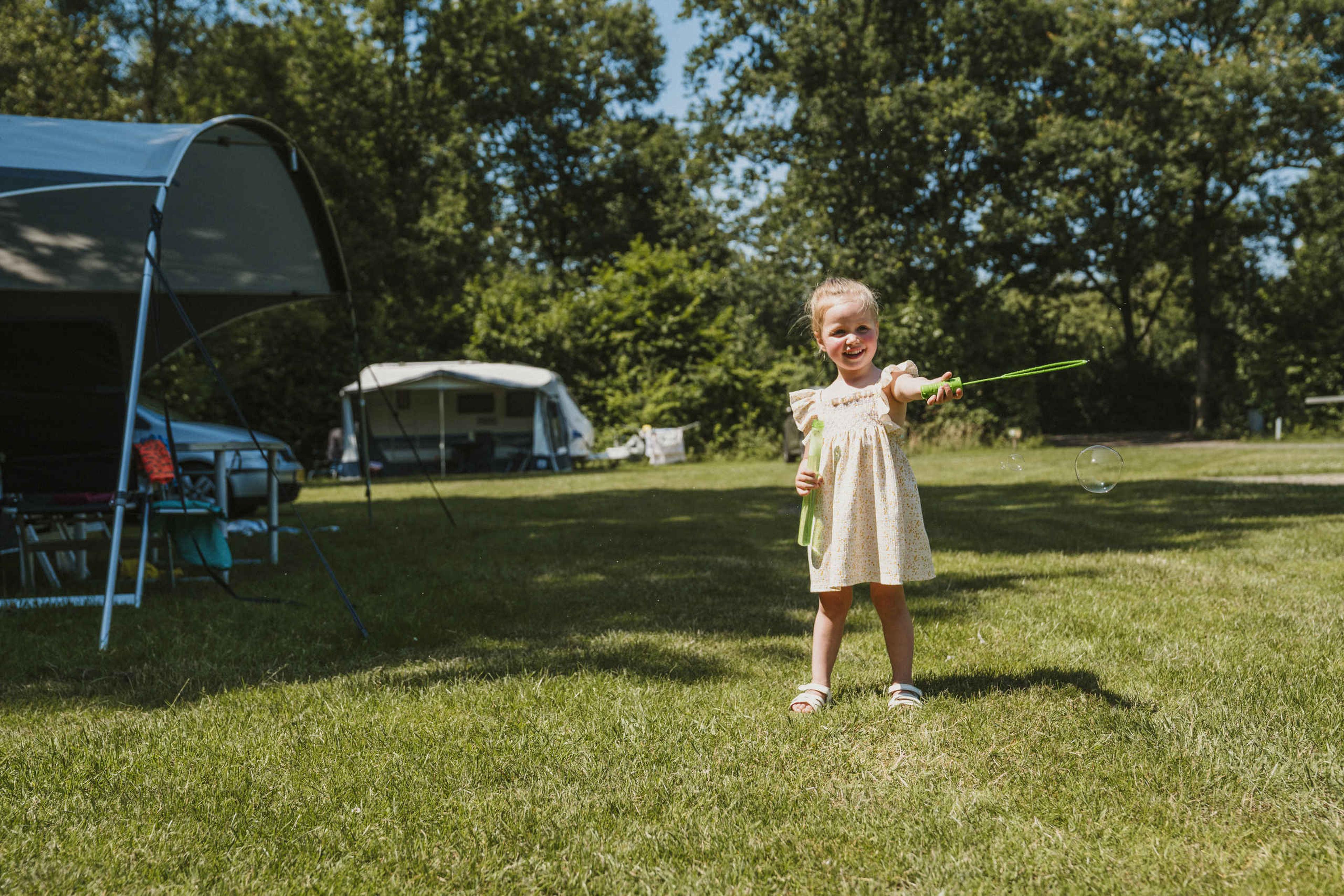 Een meisje speelt met bellenblaas op de kampeerplaats bij Vakantiepark Dierenbos