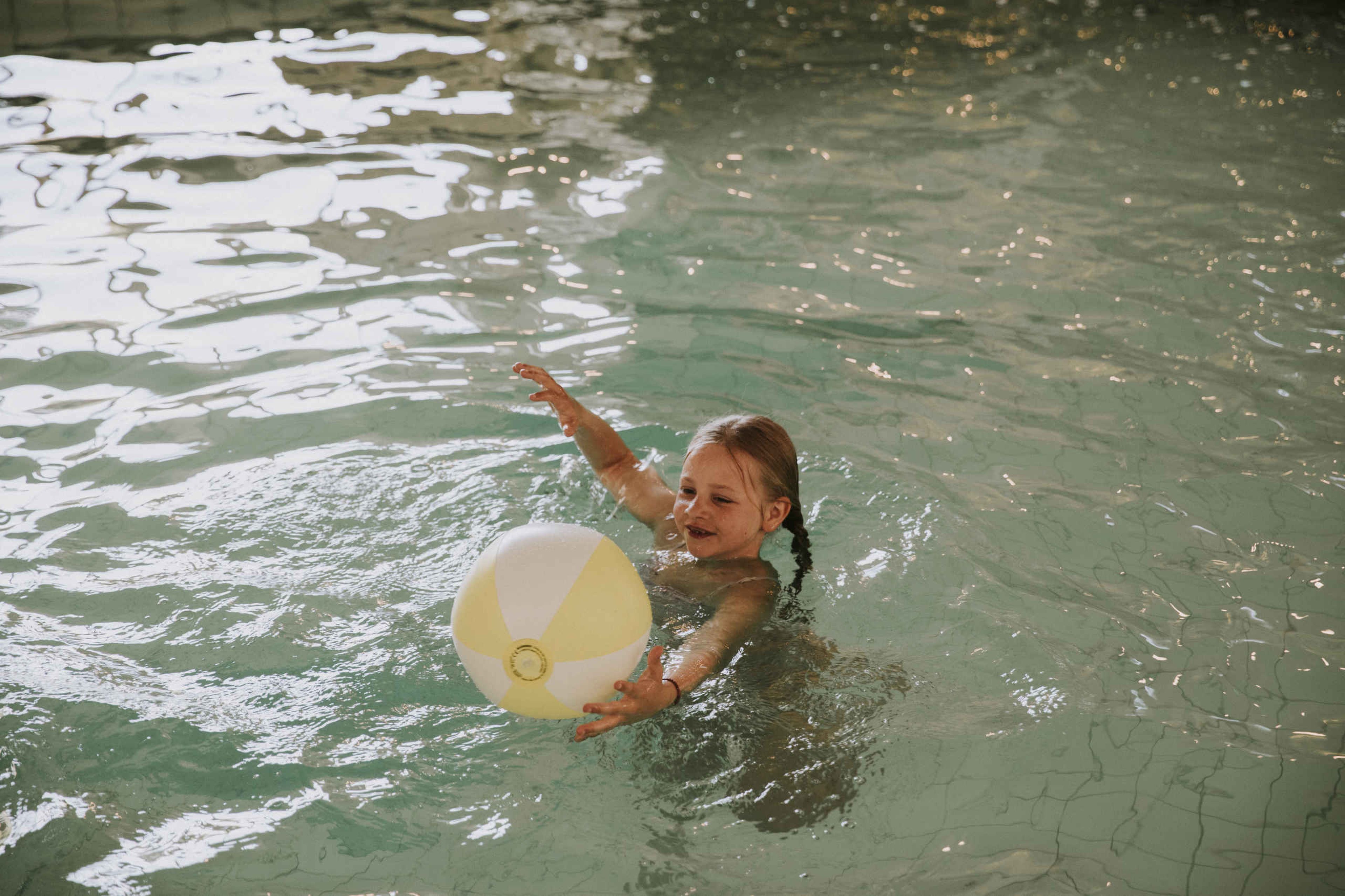 Een meisje in het zwembad van Vakantiepark Dierenbos met een gele strandbal