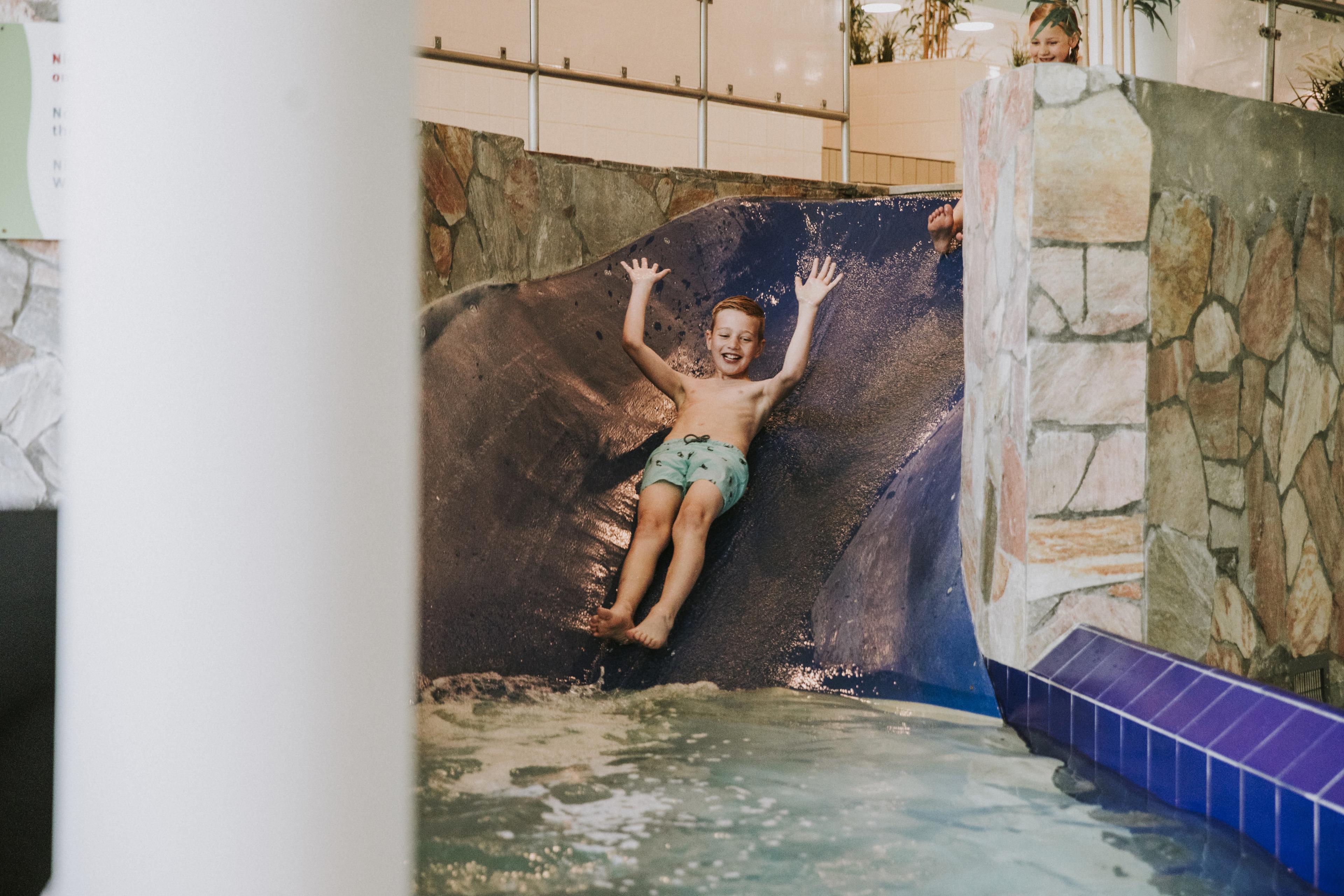 Kind gaat van de glijbaan in het zwembad van Vakantiepark Dierenbos