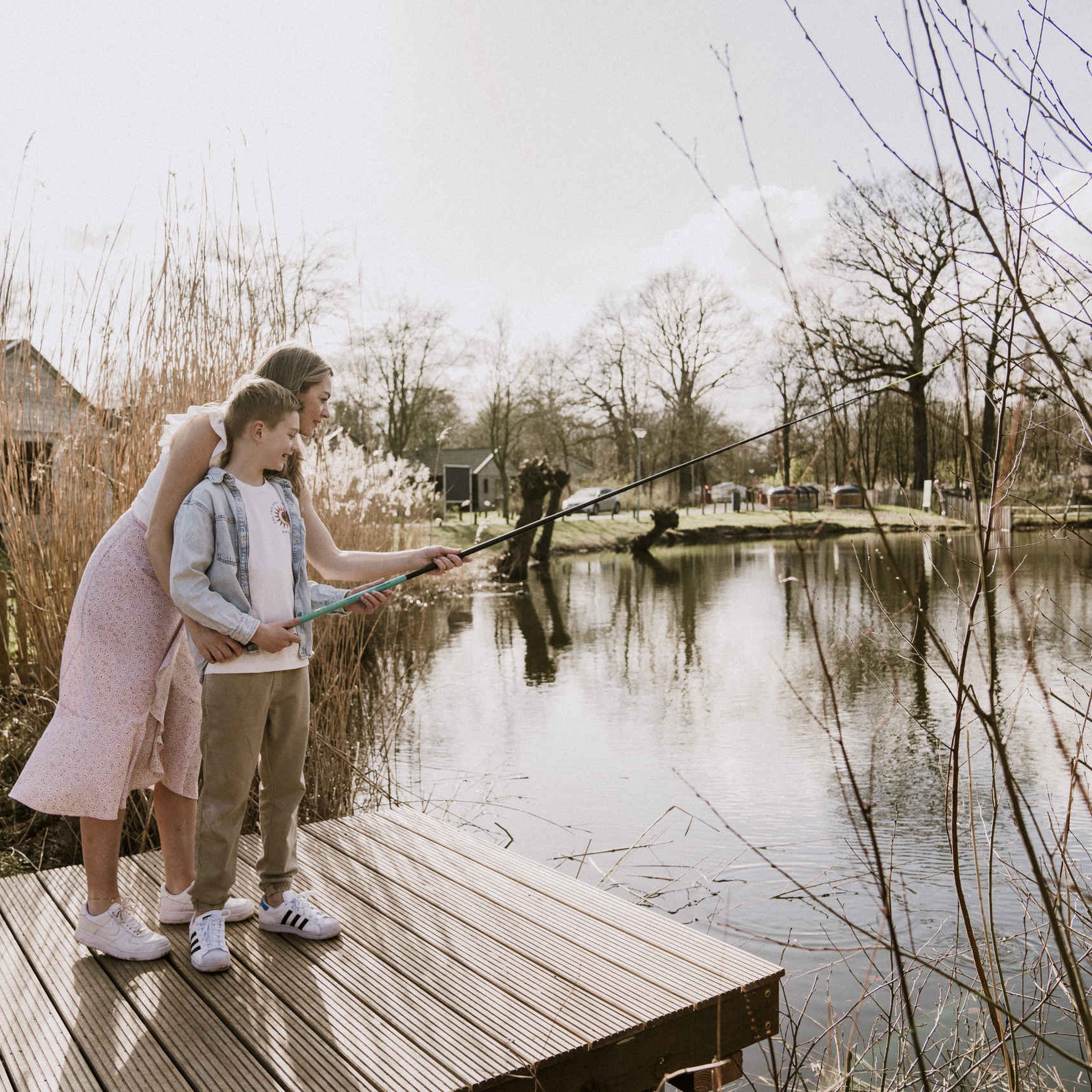 Moeder en kind met hengel op de steiger van de visvijver van Vakantiepark Dierenbos