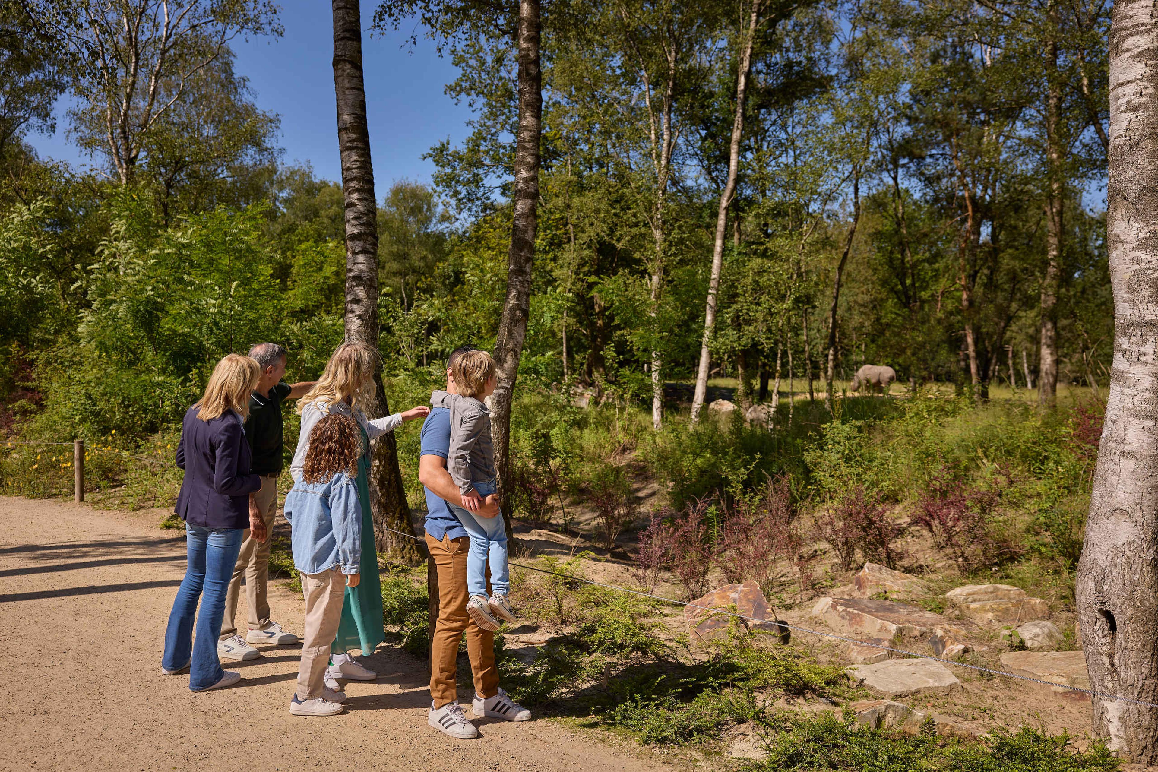 Wandelsafari gezin kijkt naar neushoorn tijdens het wandelen Safaripark Beekse Bergen