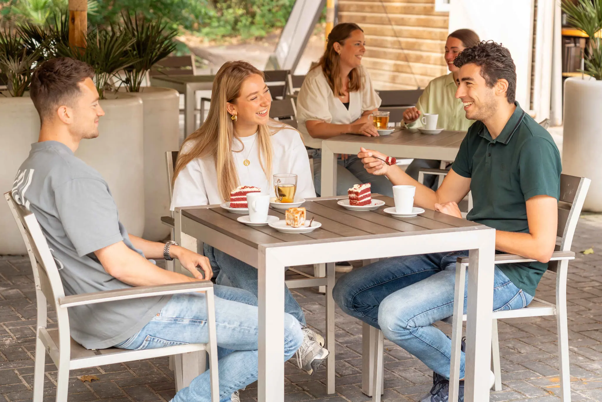 volwassenen eten en drinken op het terras bij Klimrijk Brabant