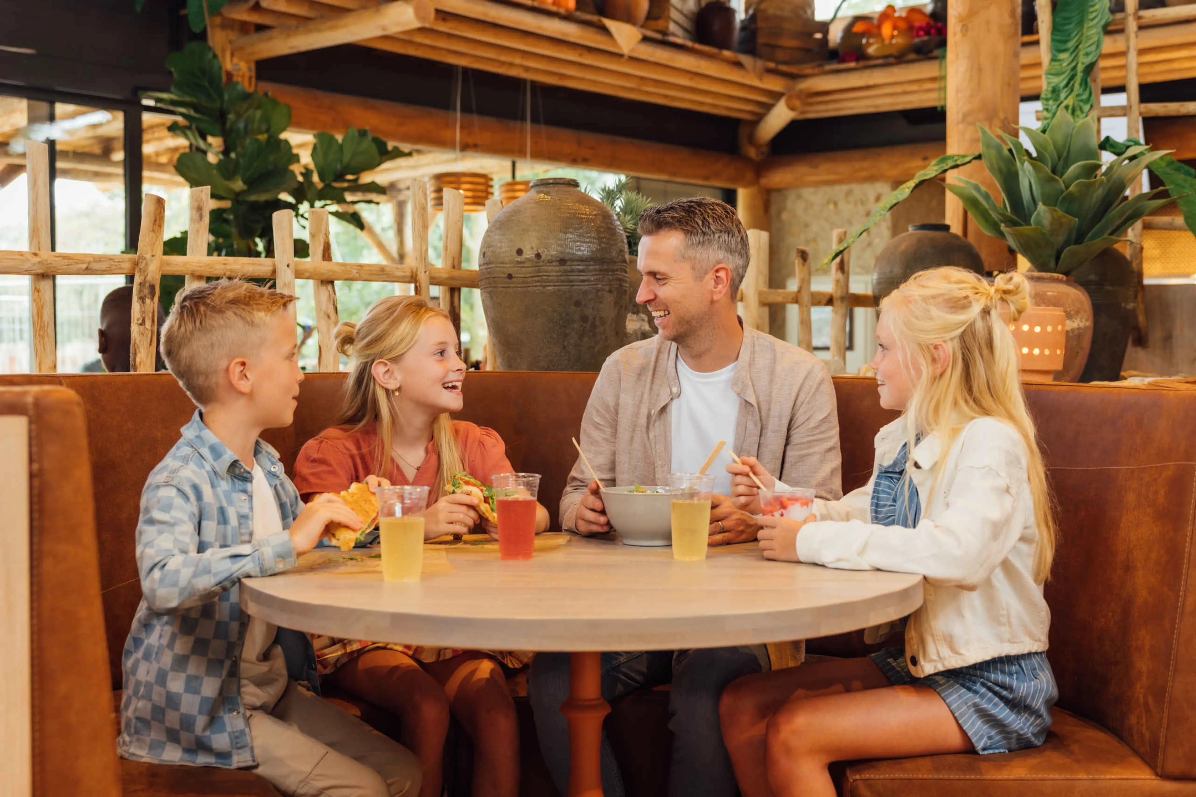 Een gezin zit te lunchen bij restaurant Mugunda in Safaripark Beekse Bergen.