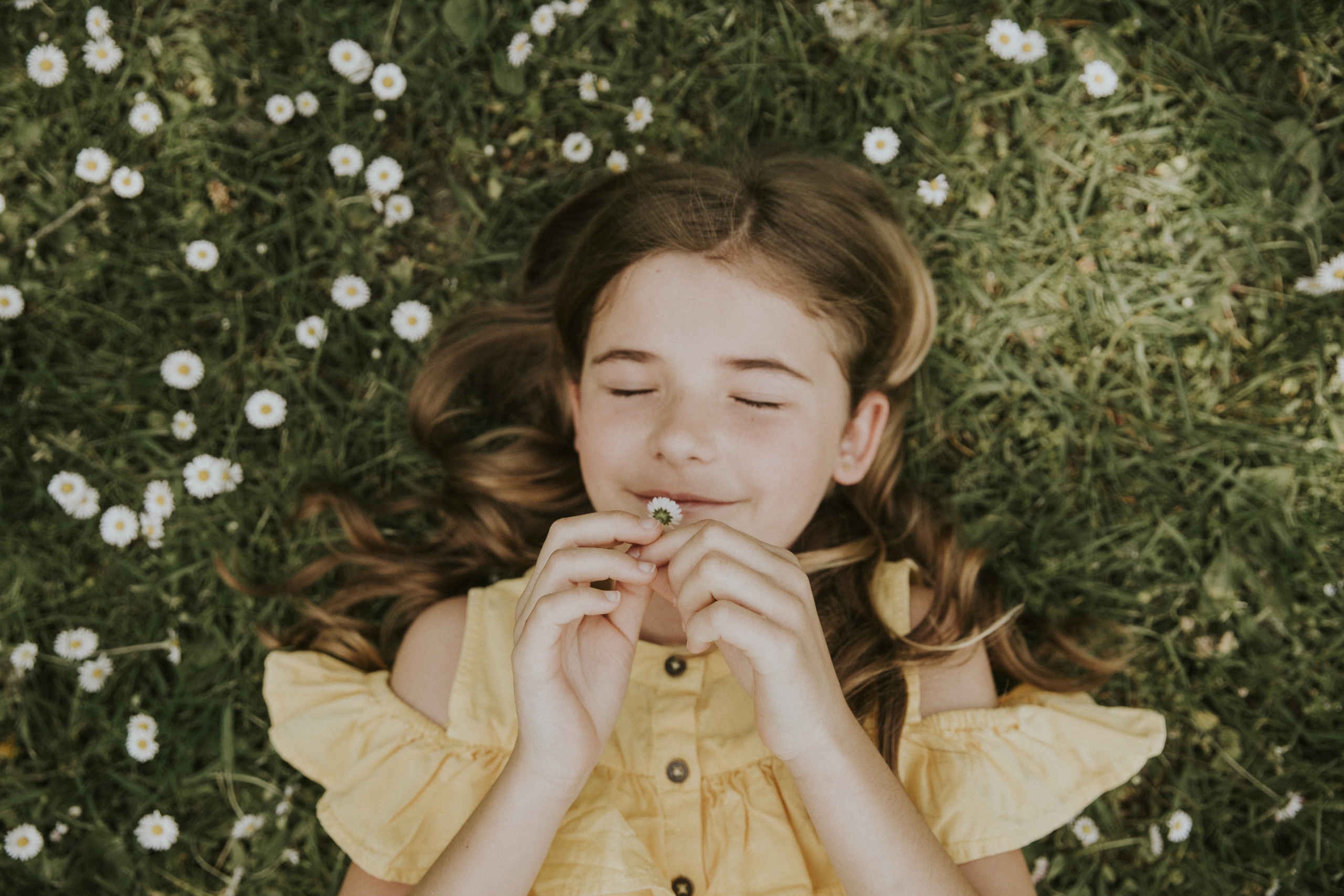 Meisje in het gras tussen de madeliefjes op Vakantiepark Dierenbos