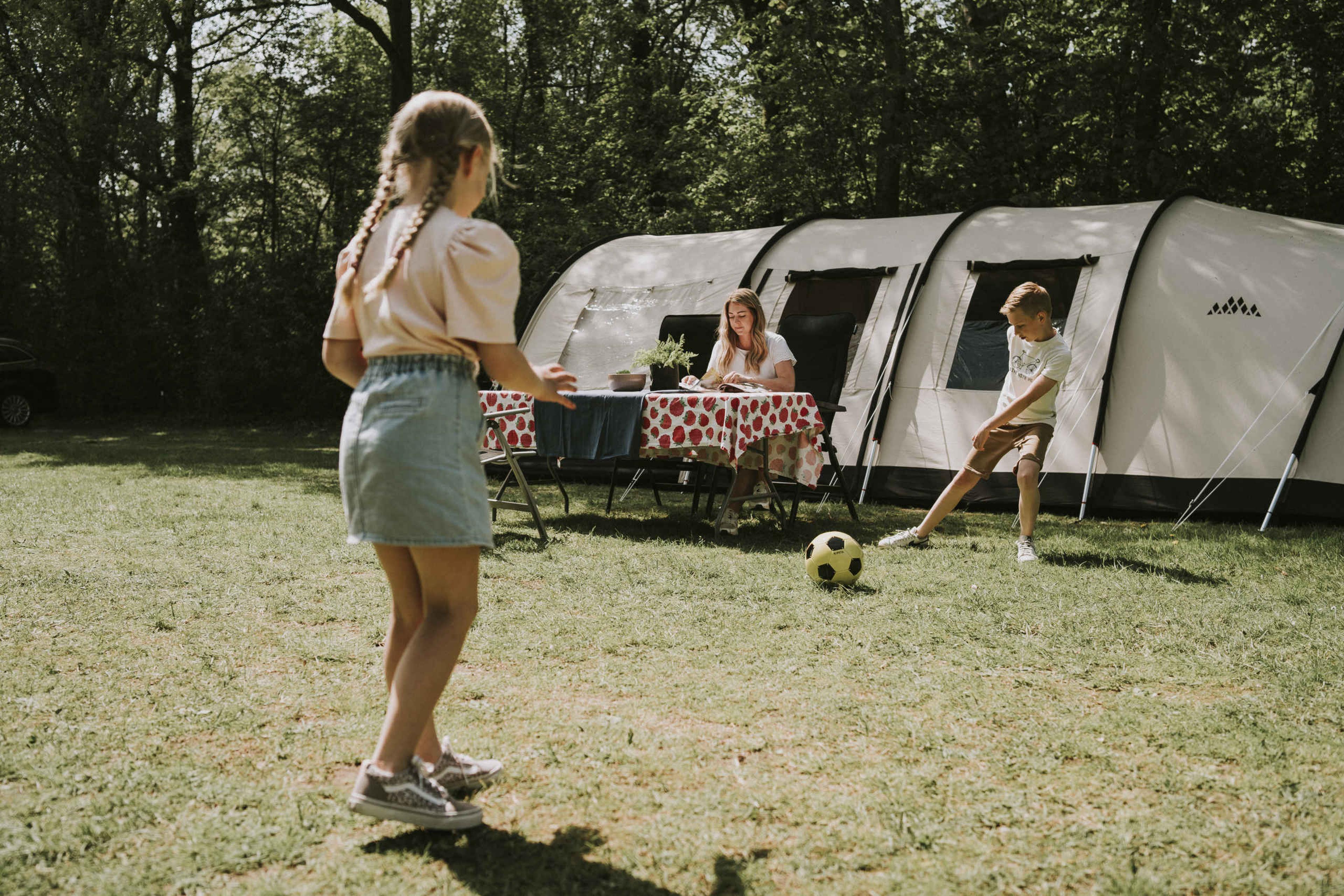 Kinderen voetballen bij de tent op de camping van Vakantiepark Dierenbos
