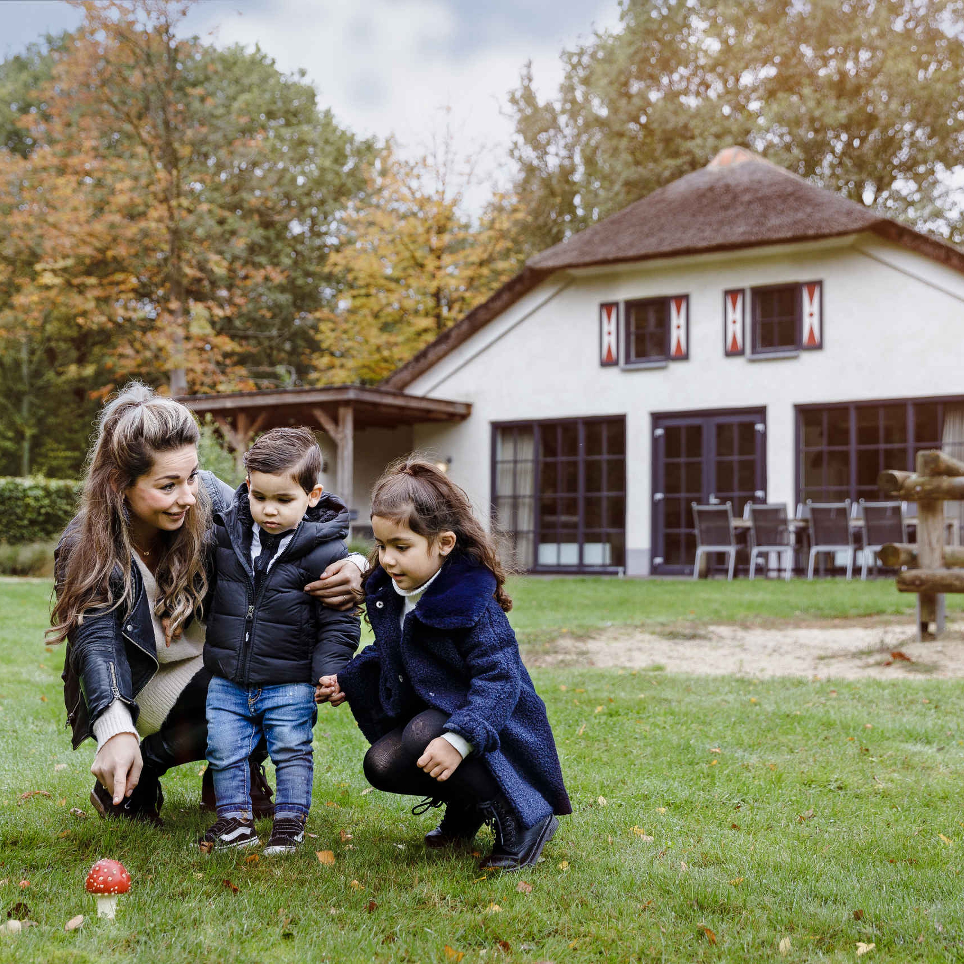 Gezin bij paddenstoel in het gras op Vakantiepark Dierenbos