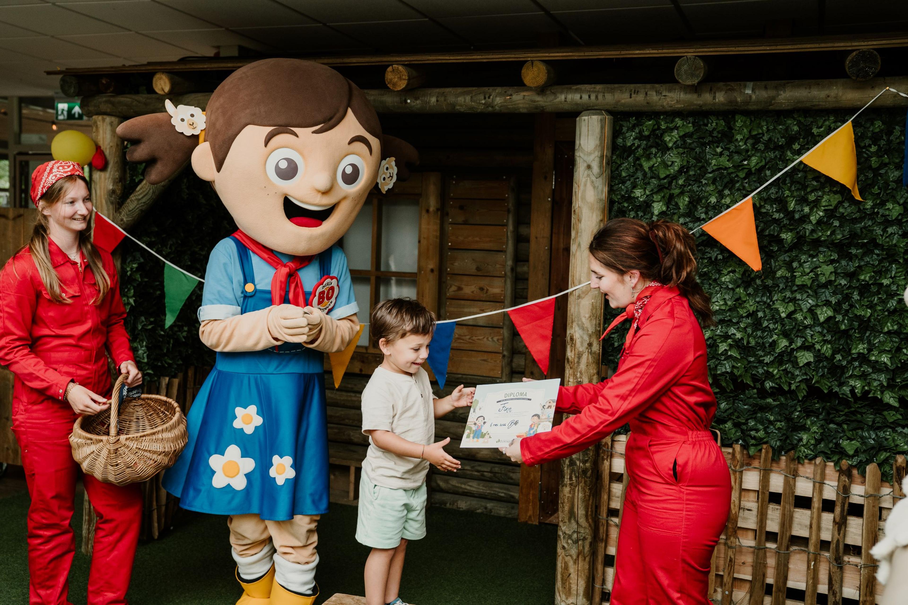 Een jongen ontvangt zijn certificaat tot dierenverzorger bij Vakantiepark Dierenbos.