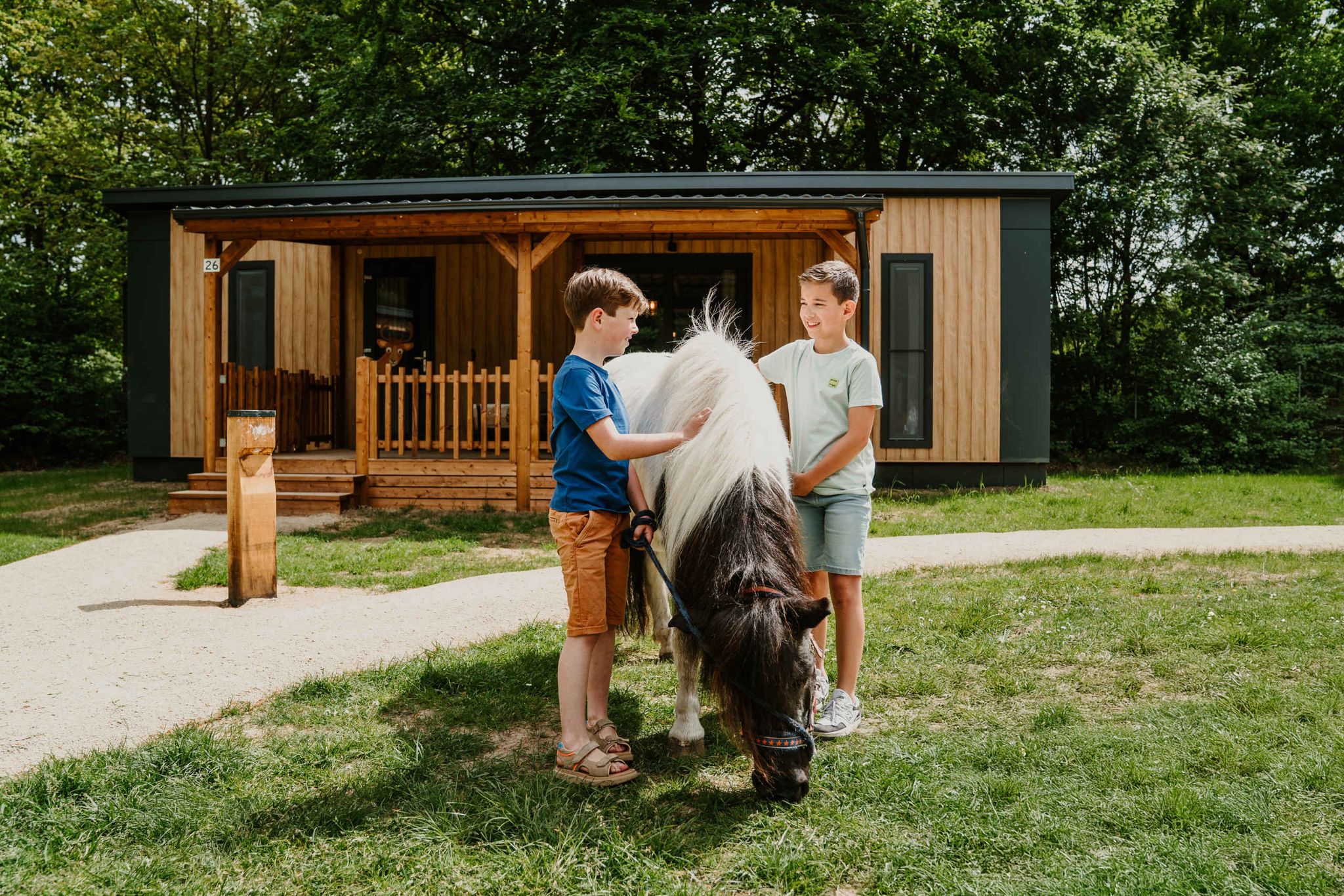 Twee jongens staan met een pony voor Cottage Edelhert bij Vakantiepark Dierenbos.