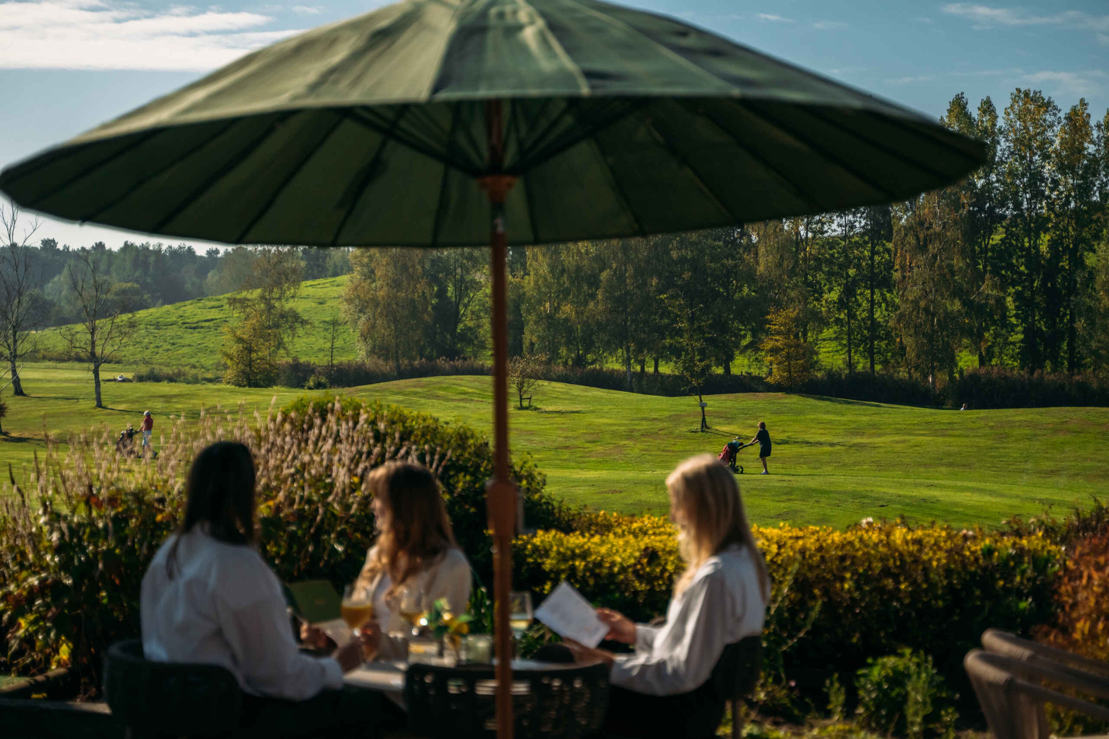 Een uitzicht op golfers op de golfbaan vanaf het terras bij Golf De Gulbergen