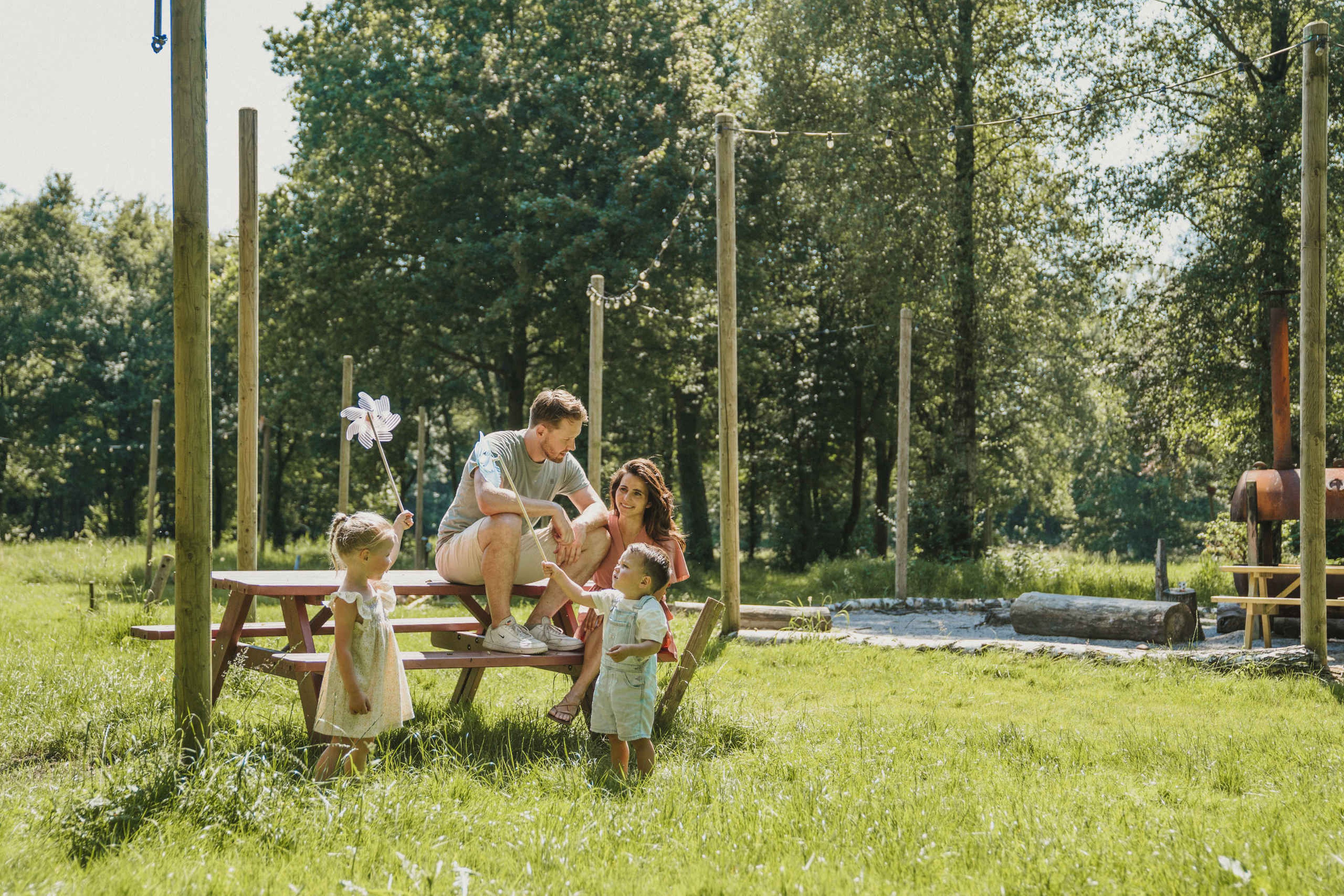 Een gezin speelt aan de eettafel bij belevingscamping Vuurvlinder bij Vakantiepark Dierenbos