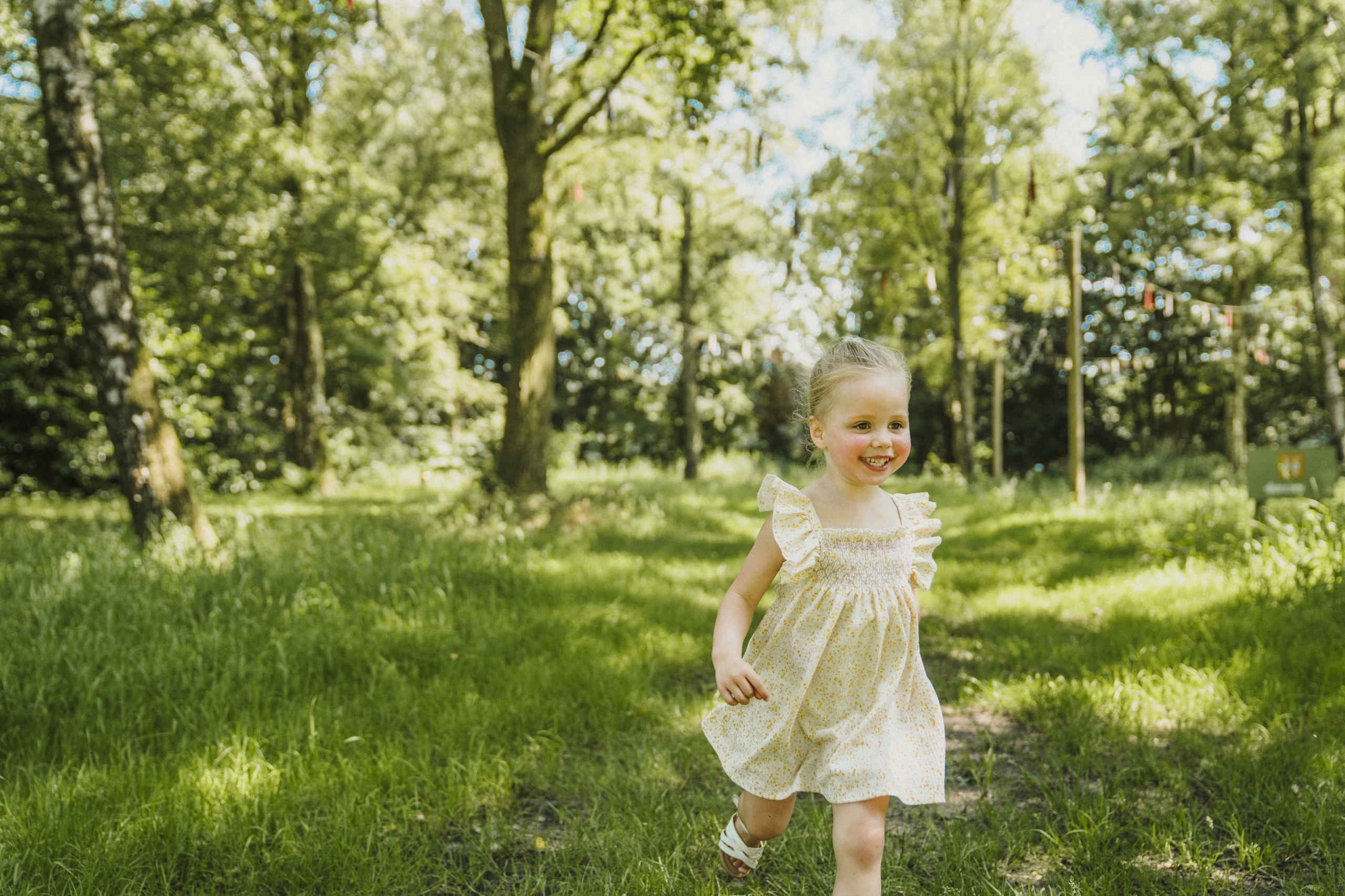 Een meisje rent door het gras bij belevingscamping Vuurvlinder bij Vakantiepark Dierenbos