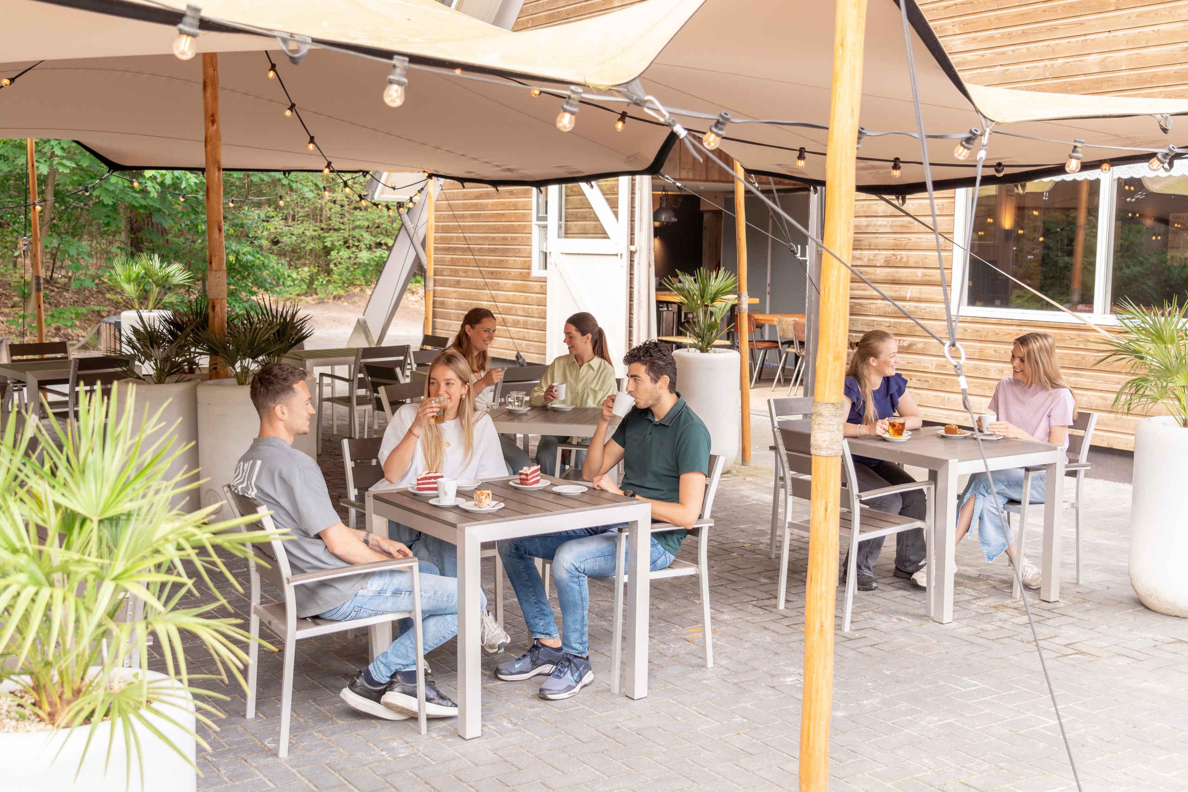 Een vriendengroep aan het eten en drinken bij het boscafé van Klimrijk Brabant