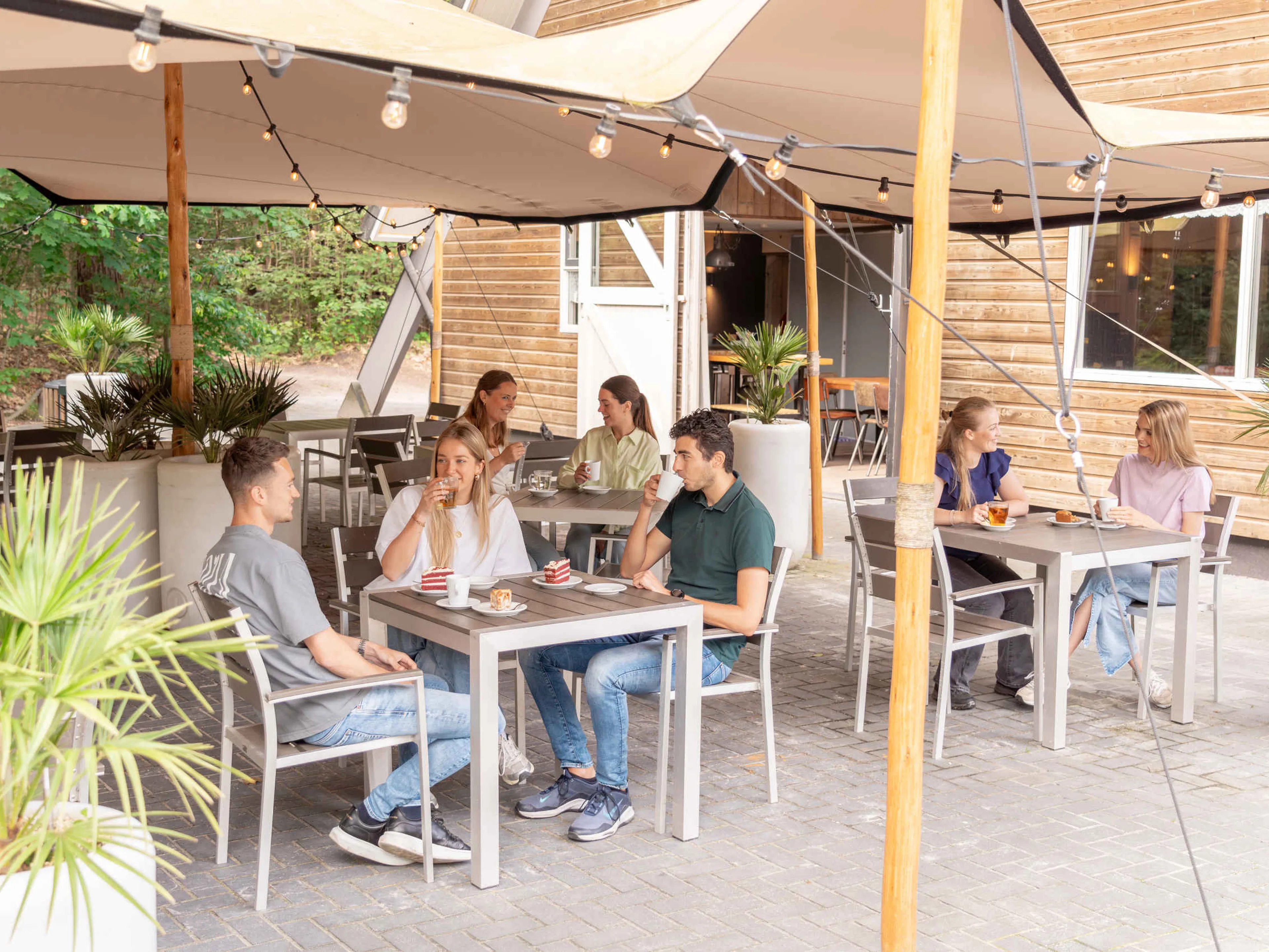 Een vriendengroep aan het eten en drinken bij het boscafé van Klimrijk Brabant