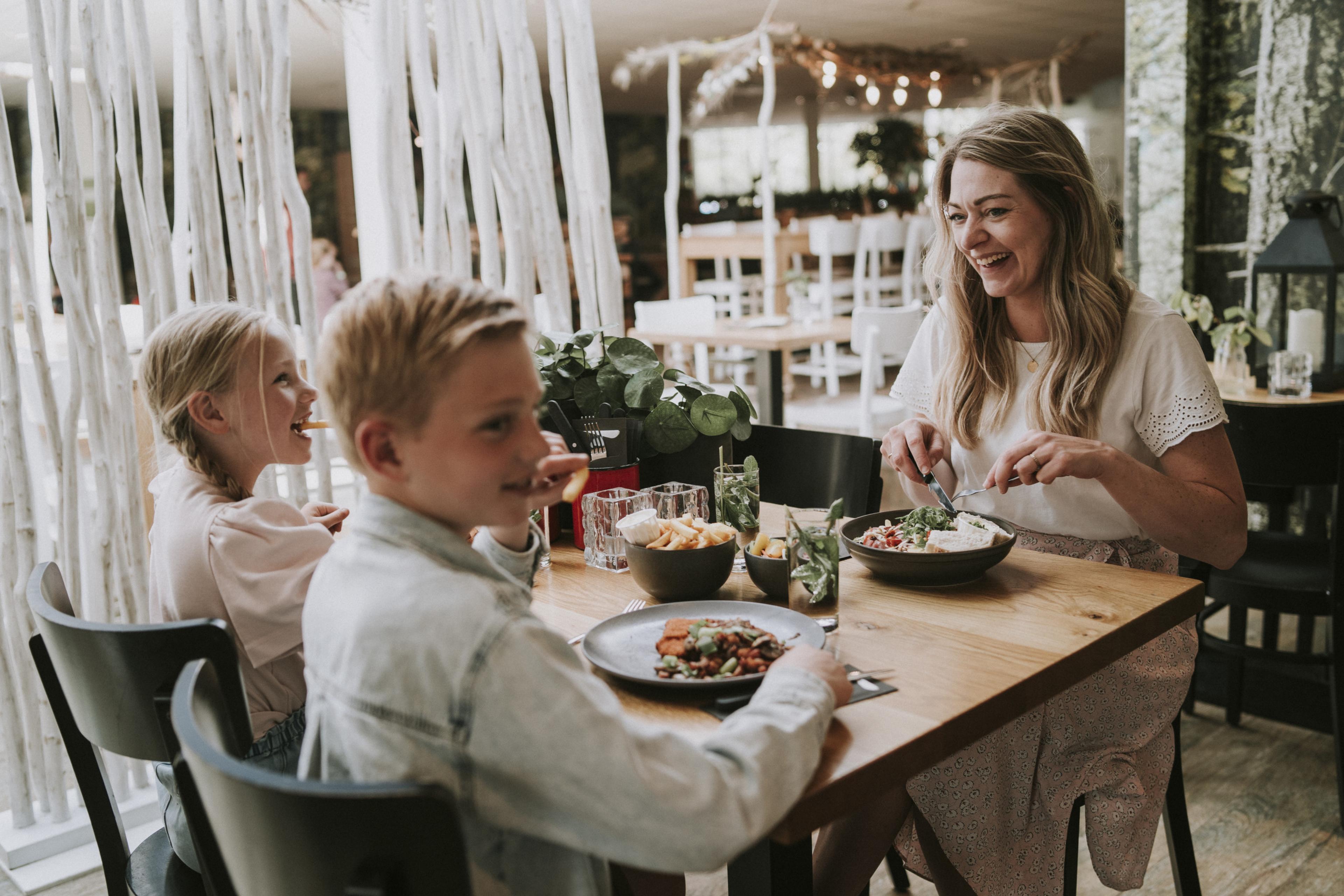 Moeder en kinderen aan het lunchen in het restaurant bij Vakantiepark Dierenbos