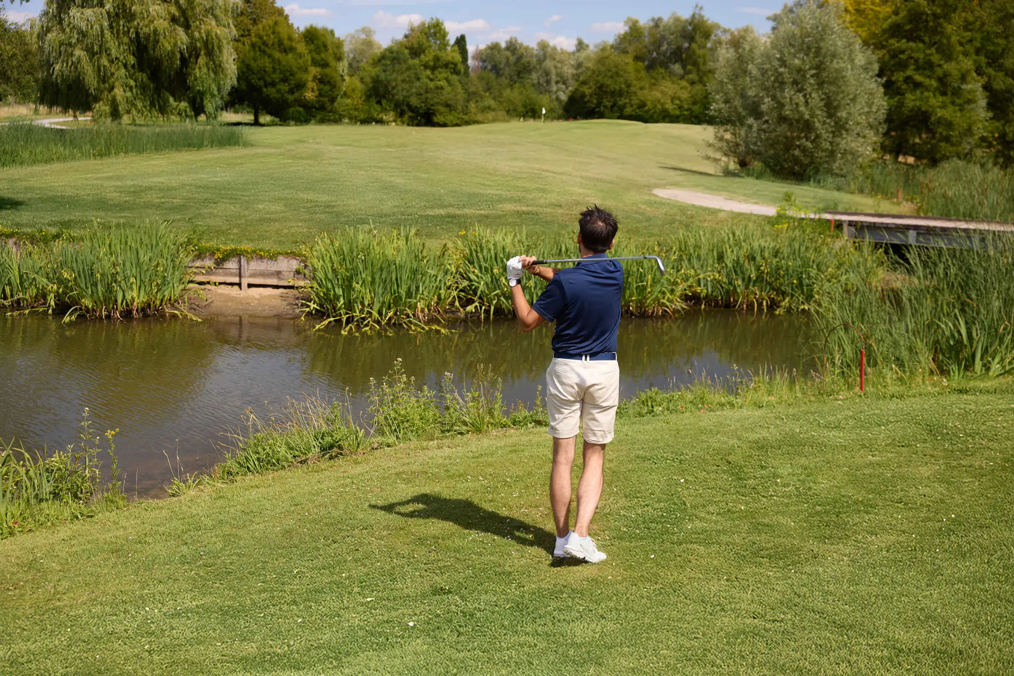 Een man slaat zijn bal over het water op hole 16 van de libellebaan bij Golf De Gulbergen