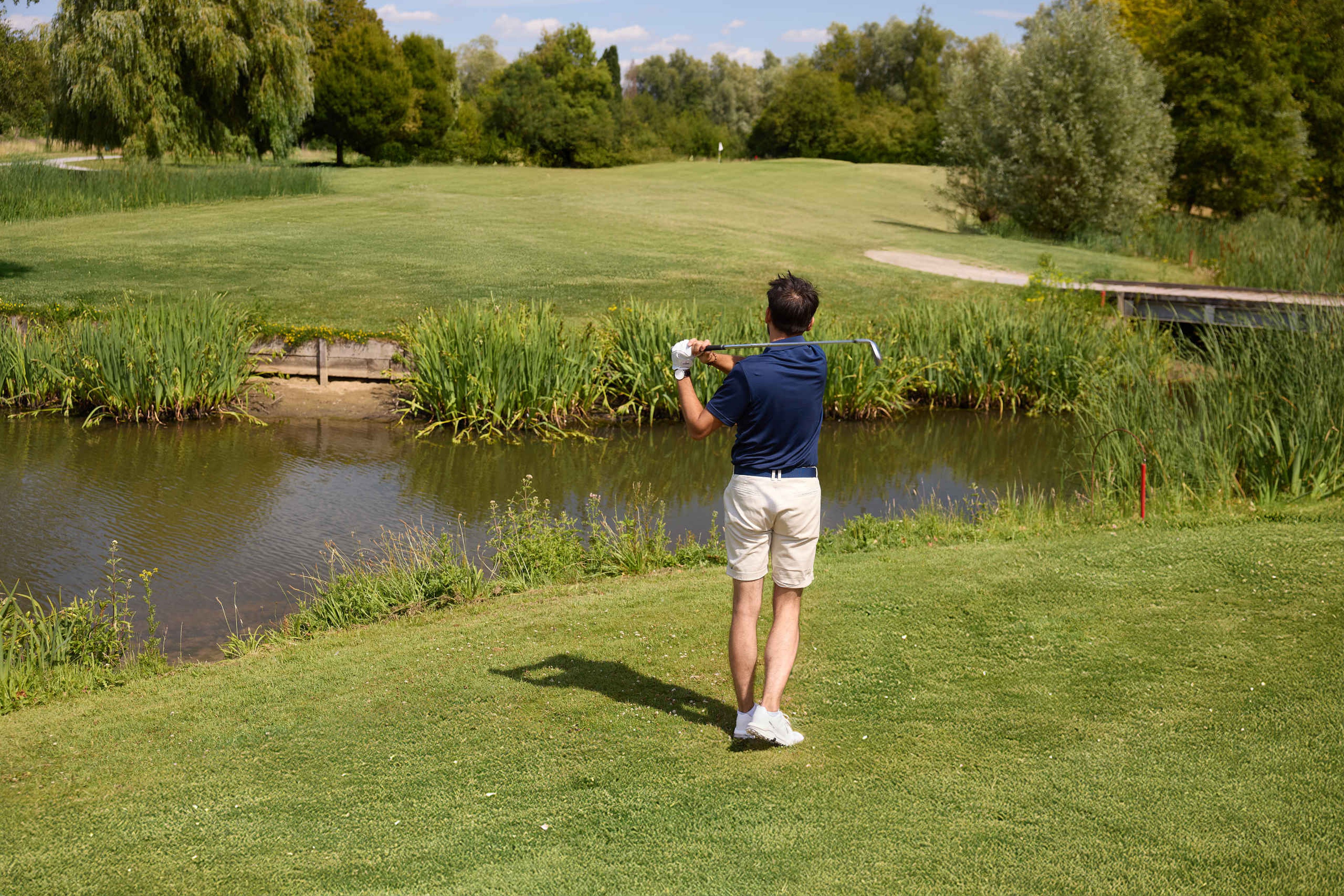 Een man slaat zijn bal over het water op hole 16 van de libellebaan bij Golf De Gulbergen