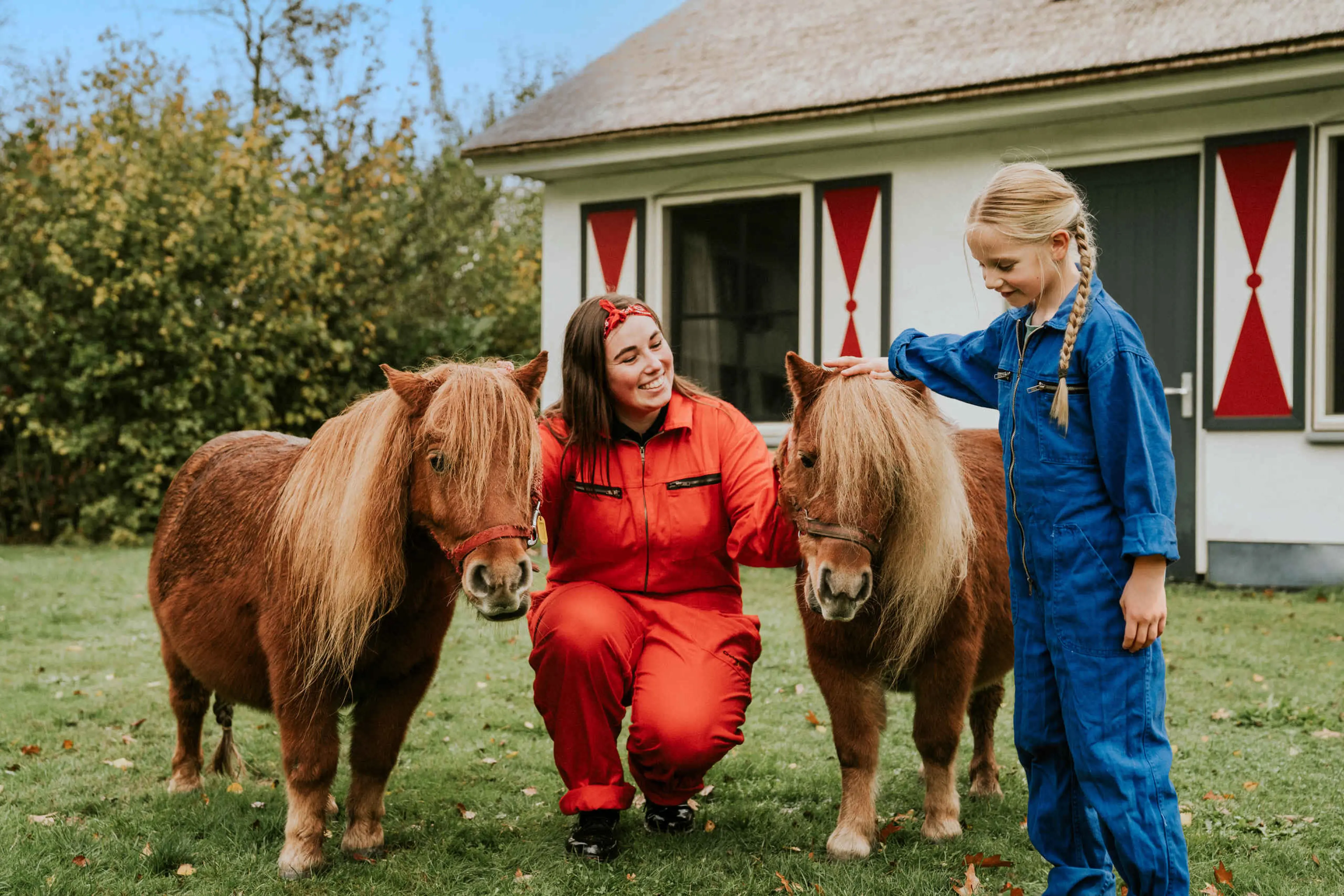 Een dierenverzorger en een meisje staan bij de pony's bij Vakantiepark Dierenbos