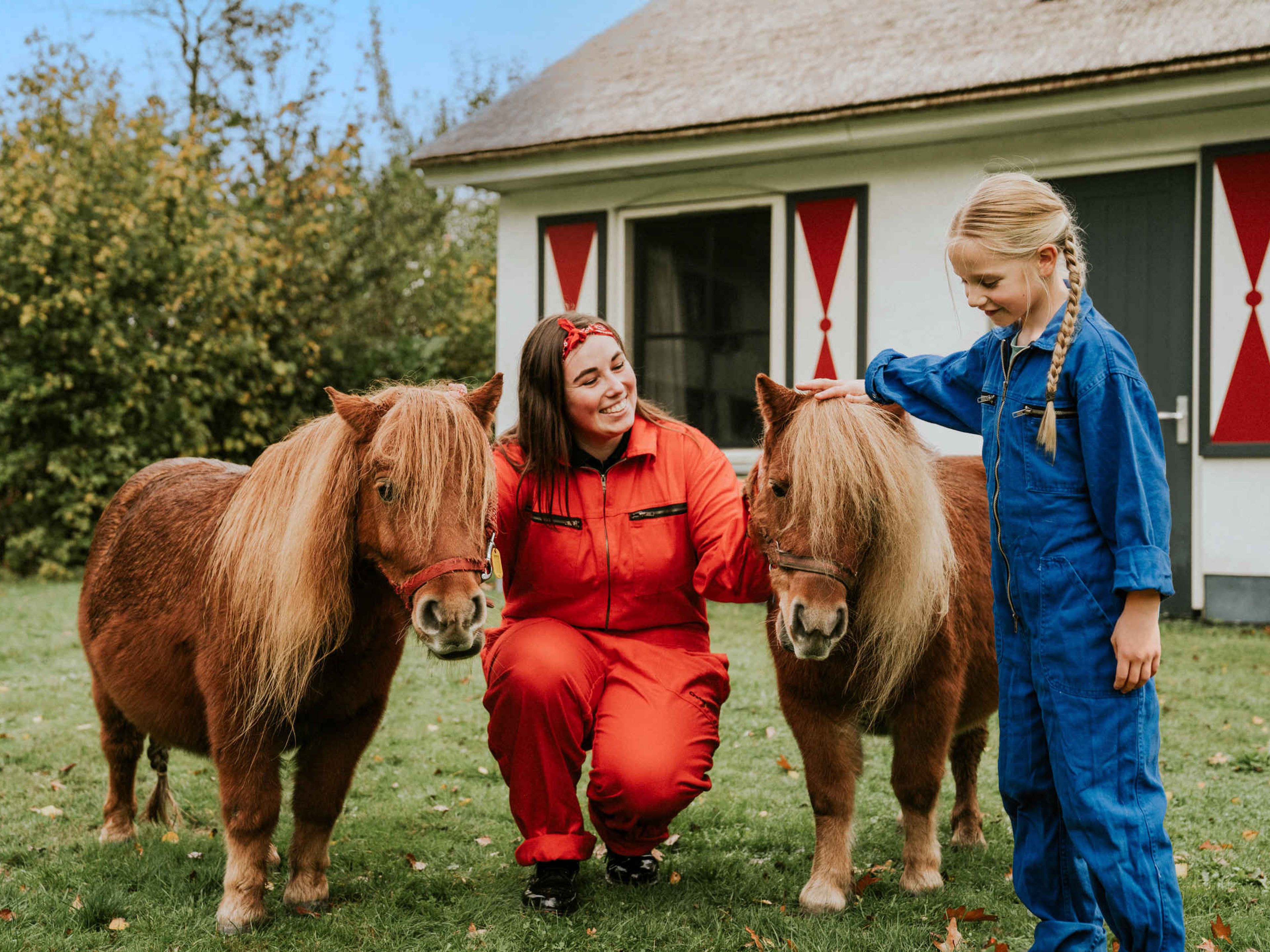 Een dierenverzorger en een meisje staan bij de pony's bij Vakantiepark Dierenbos