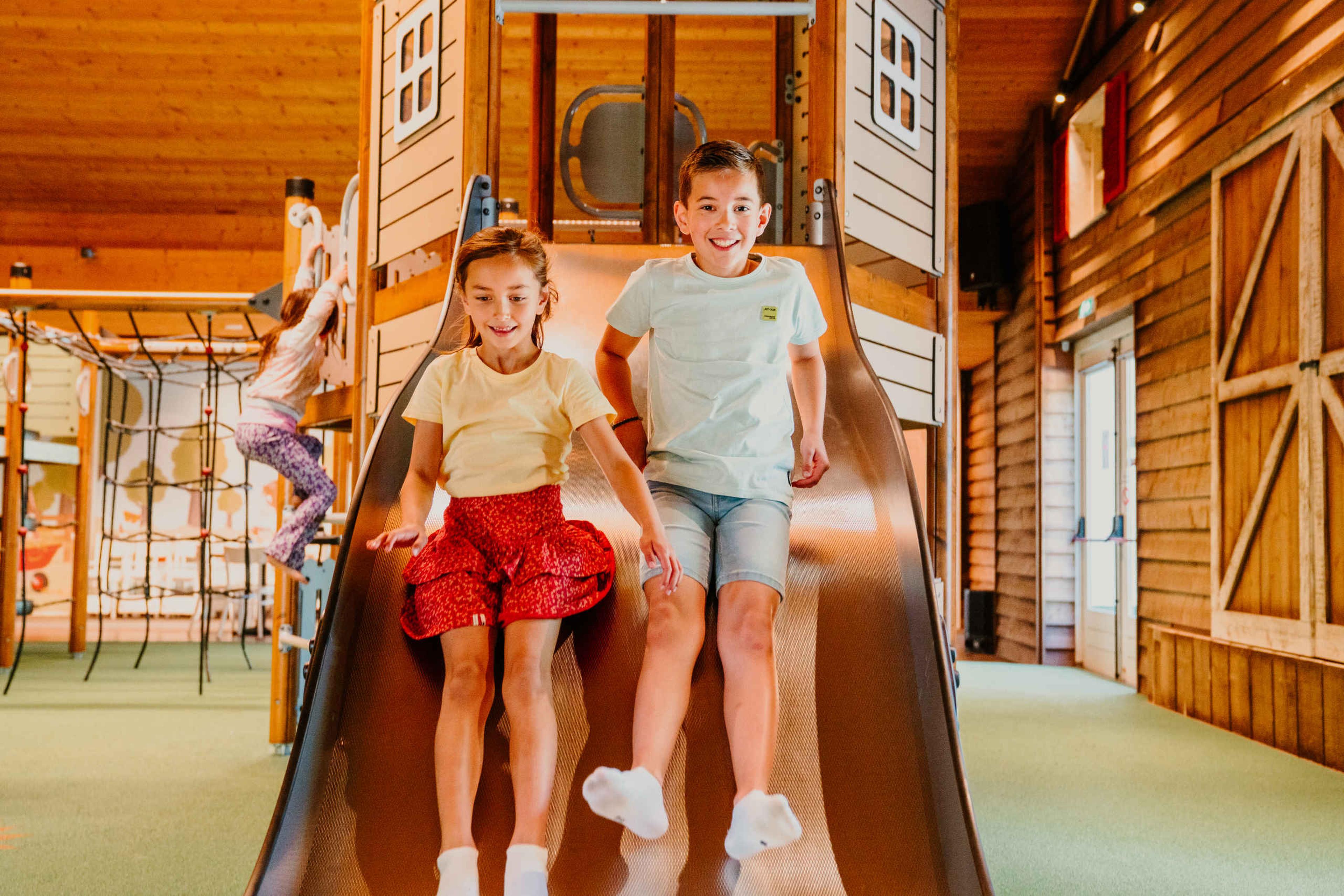 Kinderen glijden van de glijbaan in de binnenspeeltuin van Vakantiepark Dierenbos