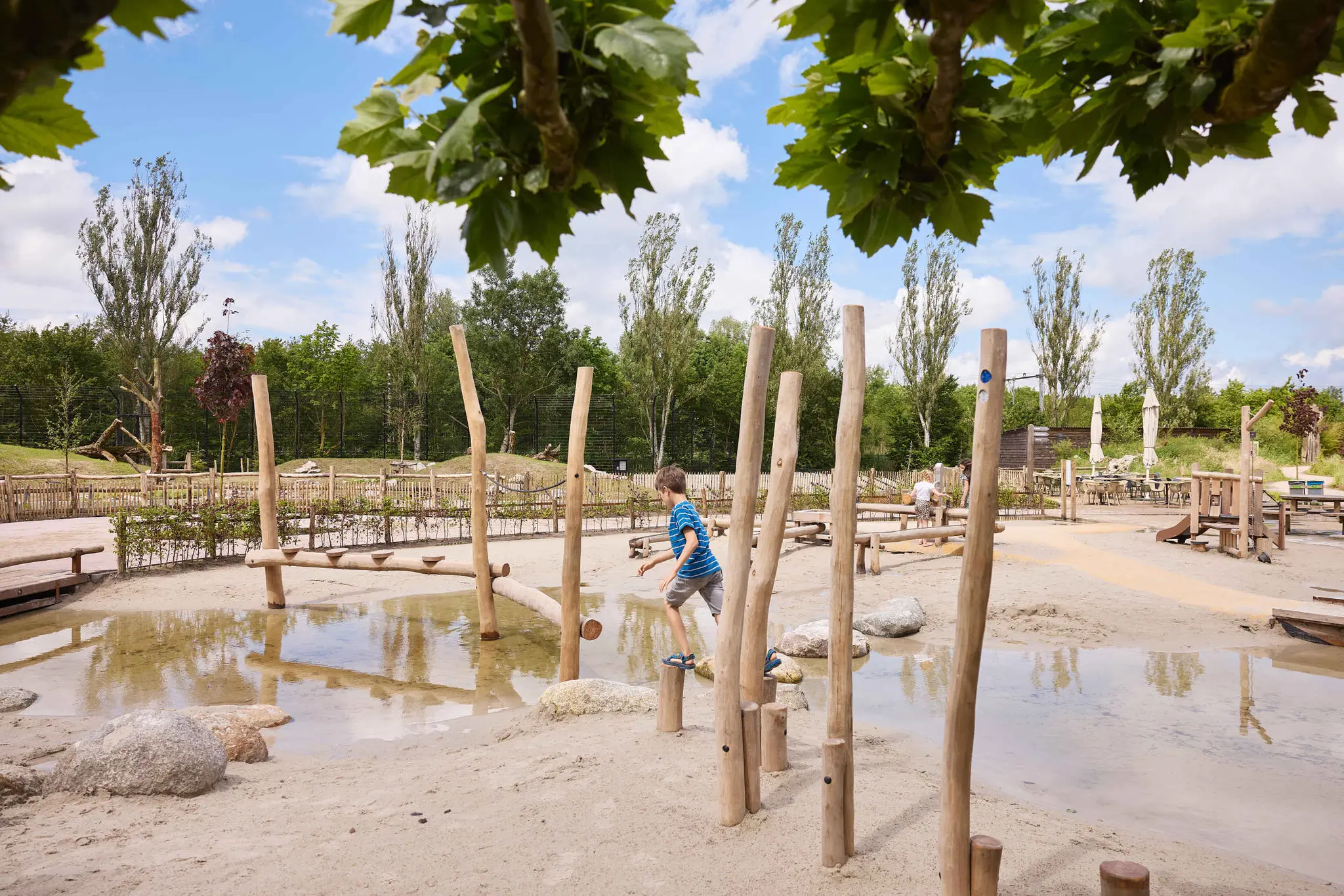 Een jongen loopt over de houten palen bij de waterspeeltuin in Eindhoven Zoo.