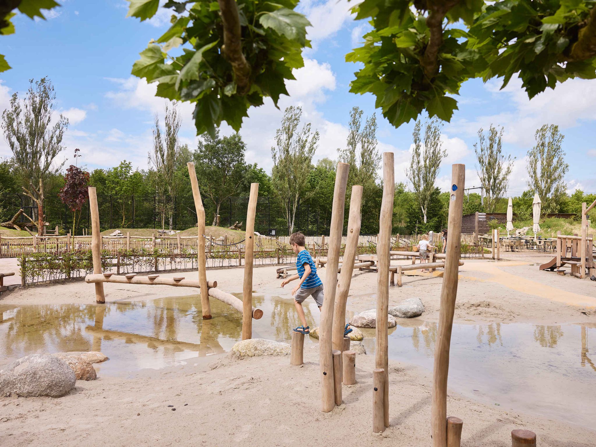Een jongen loopt over de houten palen bij de waterspeeltuin in Eindhoven Zoo.