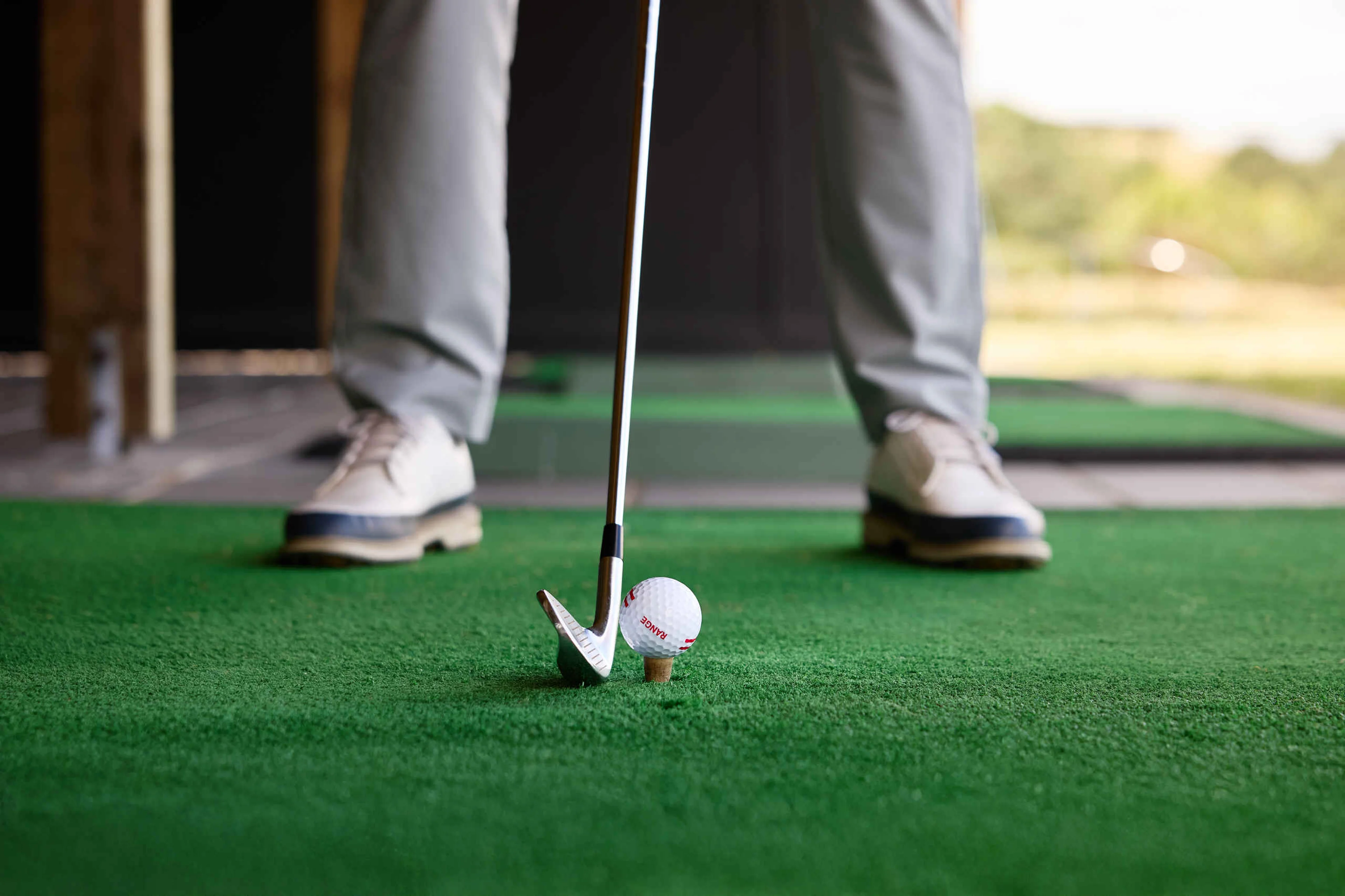 Een close-up van een golfbal en golfclub op de driving range van Golf De Gulbergen