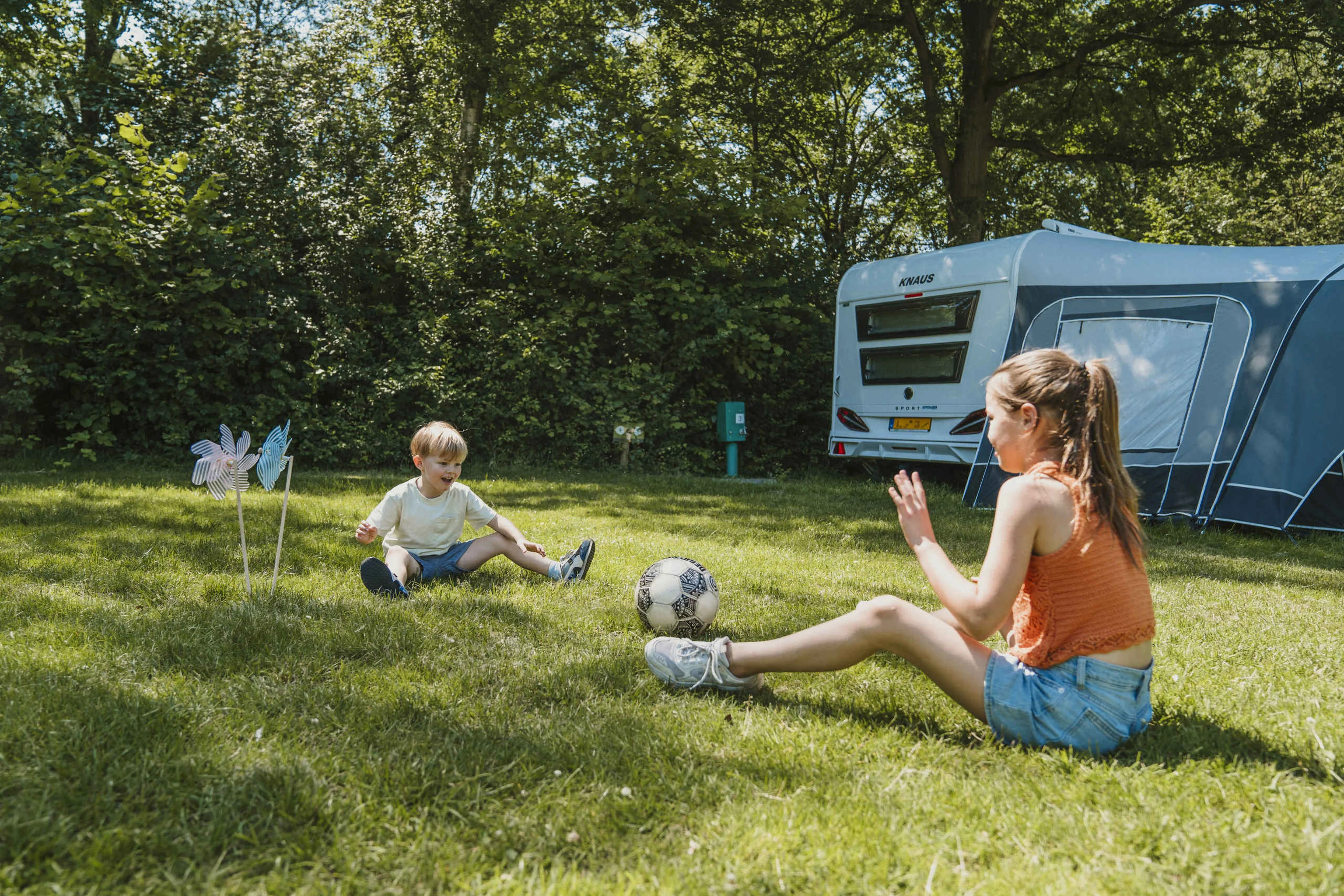 Een meisje en jongen voetballen op de kampeerplaats bij Vakantiepark Dierenbos