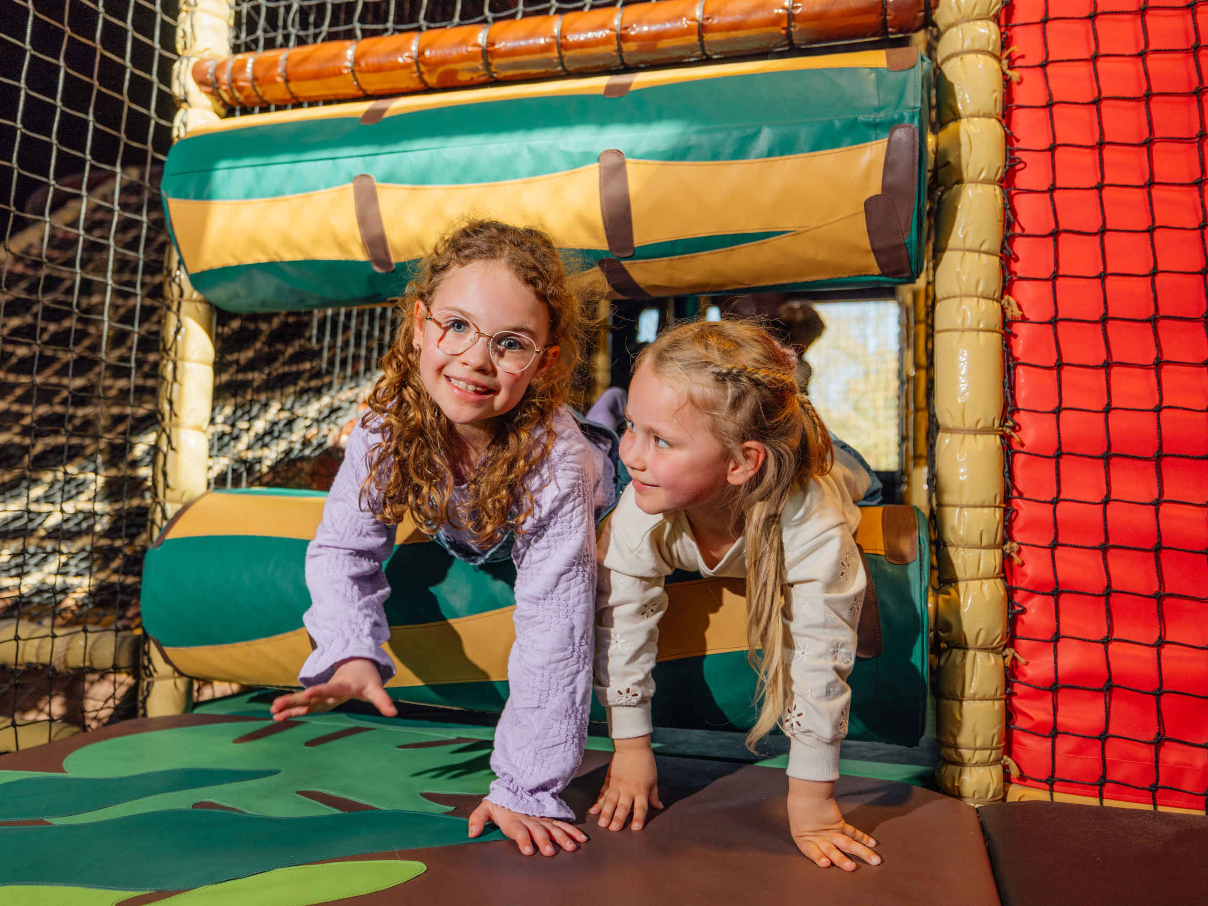 Twee kinderen klimmen door de klimtoestellen bij Speelland Indoor