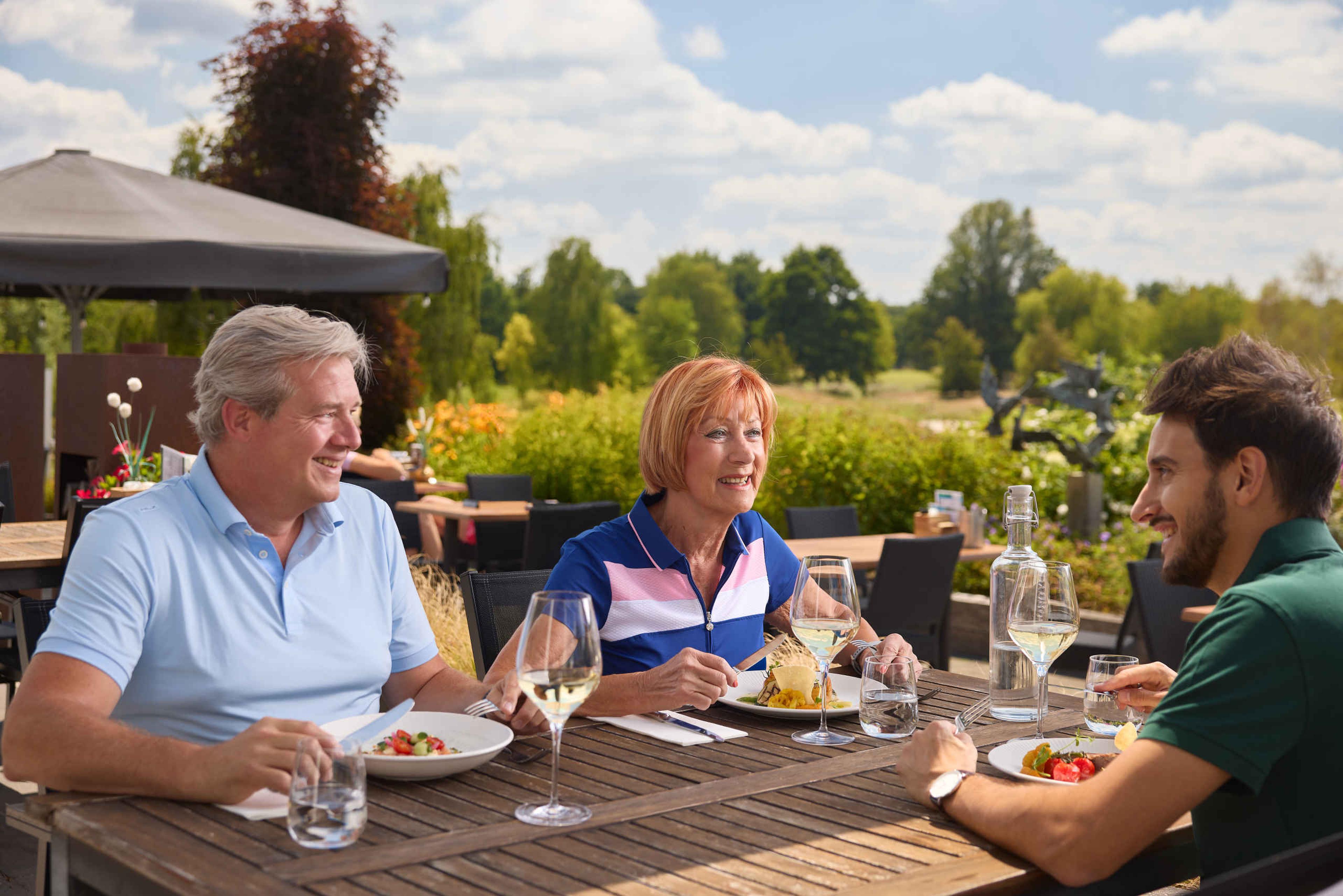 Drie volwassenen dineren op het terras van restaurant De Hooghe Bergh bij Golf De Gulbergen