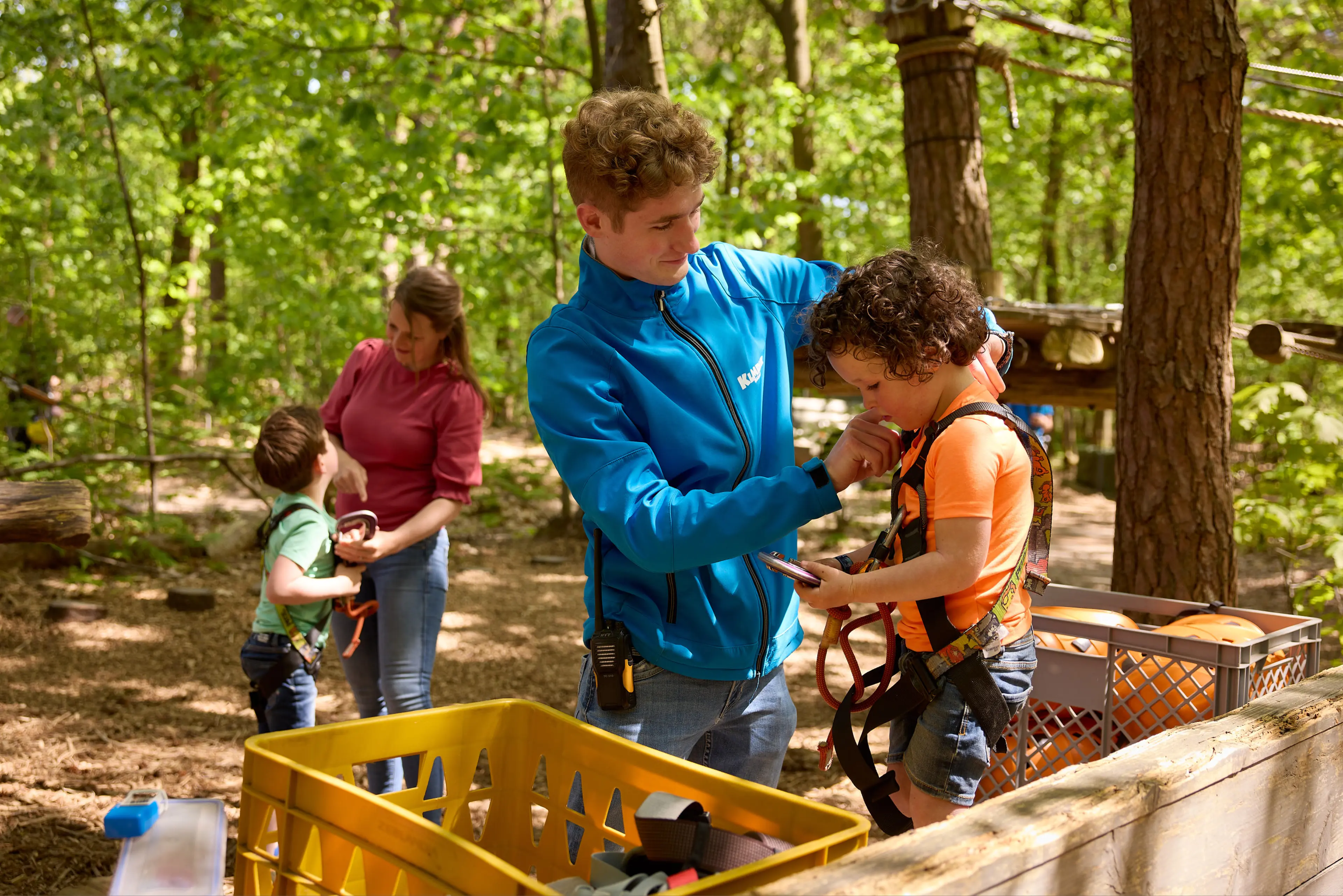 Medewerker helpt kind met klimtuig op het Pico Parcours bij Klimrijk Brabant