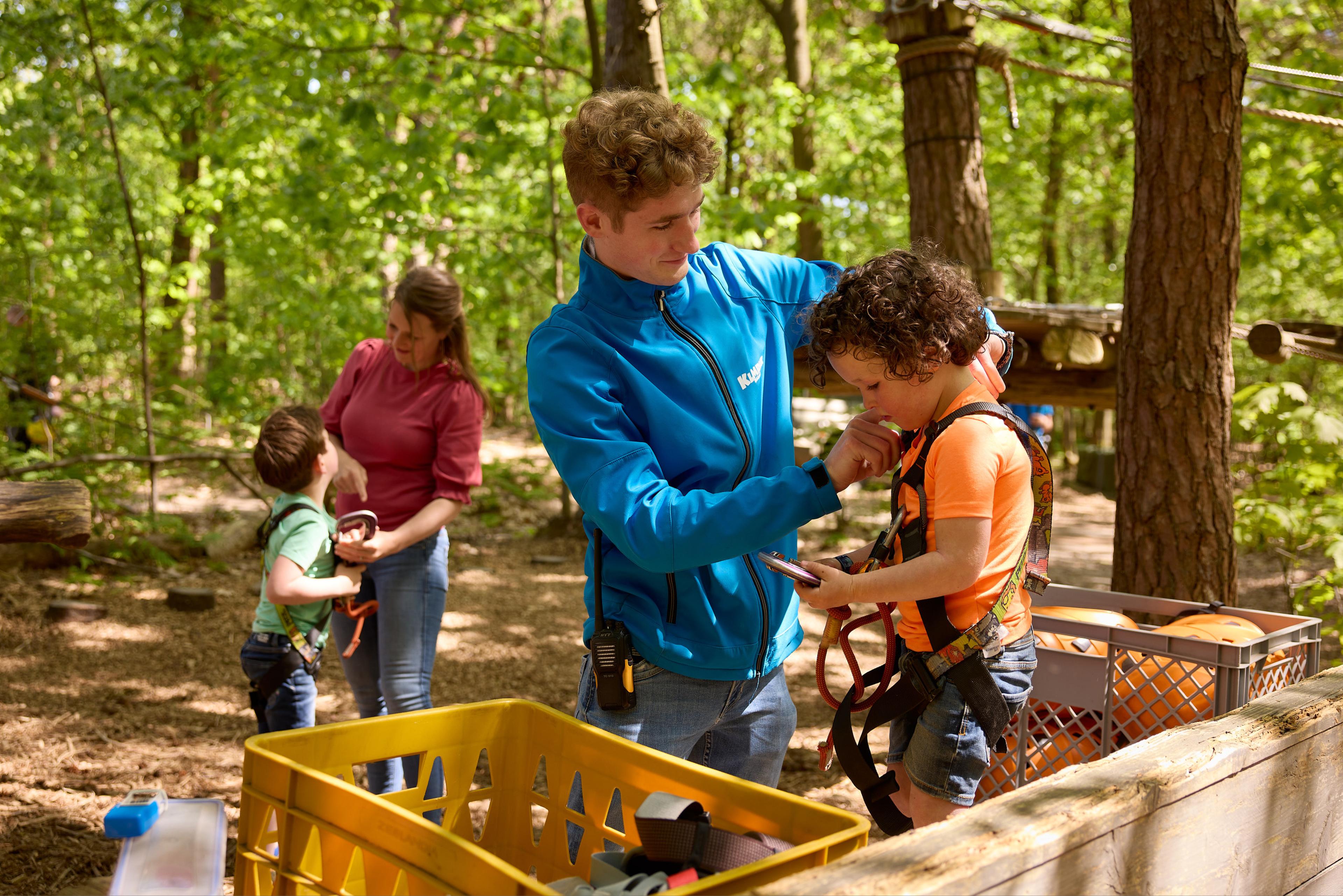 Medewerker helpt kind met klimtuig op het Pico Parcours bij Klimrijk Brabant